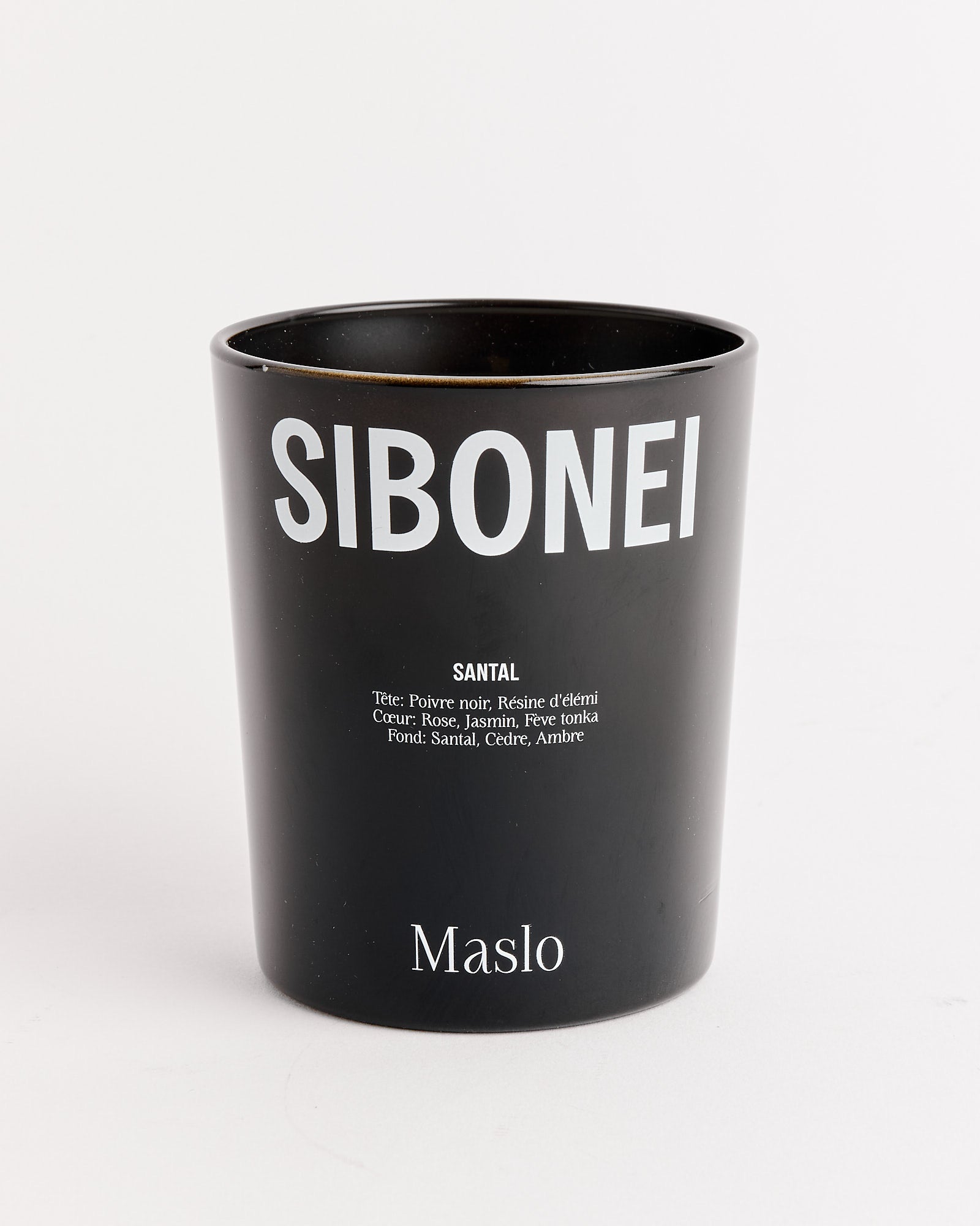 The SIBONEI Maslo (Santal) Candle comes in a black cup with white text, ideal for enjoying your favorite soy or coconut wax candle.