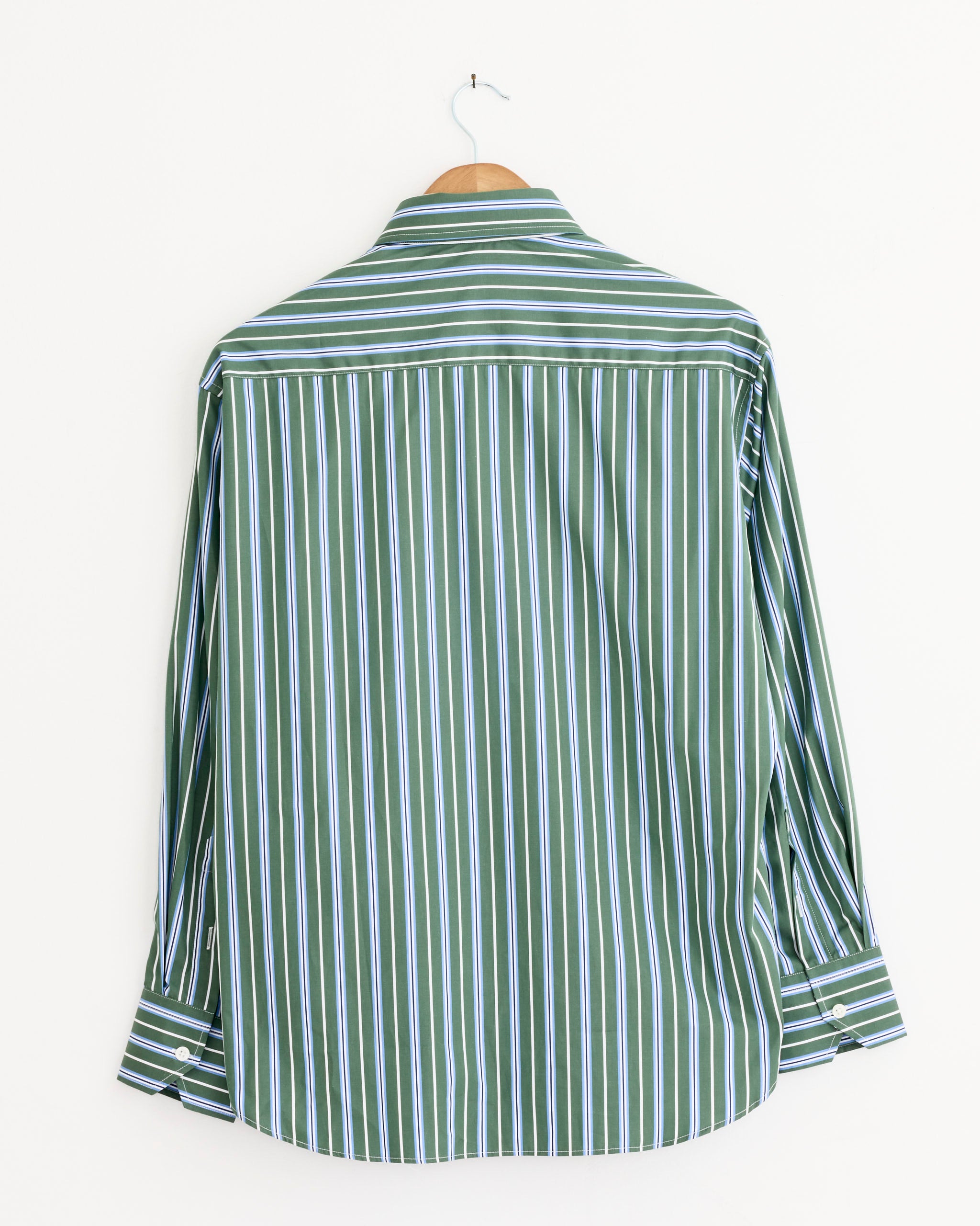 The Hommegirls Oxford Shirt in Green Porto Stripe, made of Italian cotton with white and blue vertical stripes, hangs on a wooden hanger against a plain white backdrop, shown from the back.