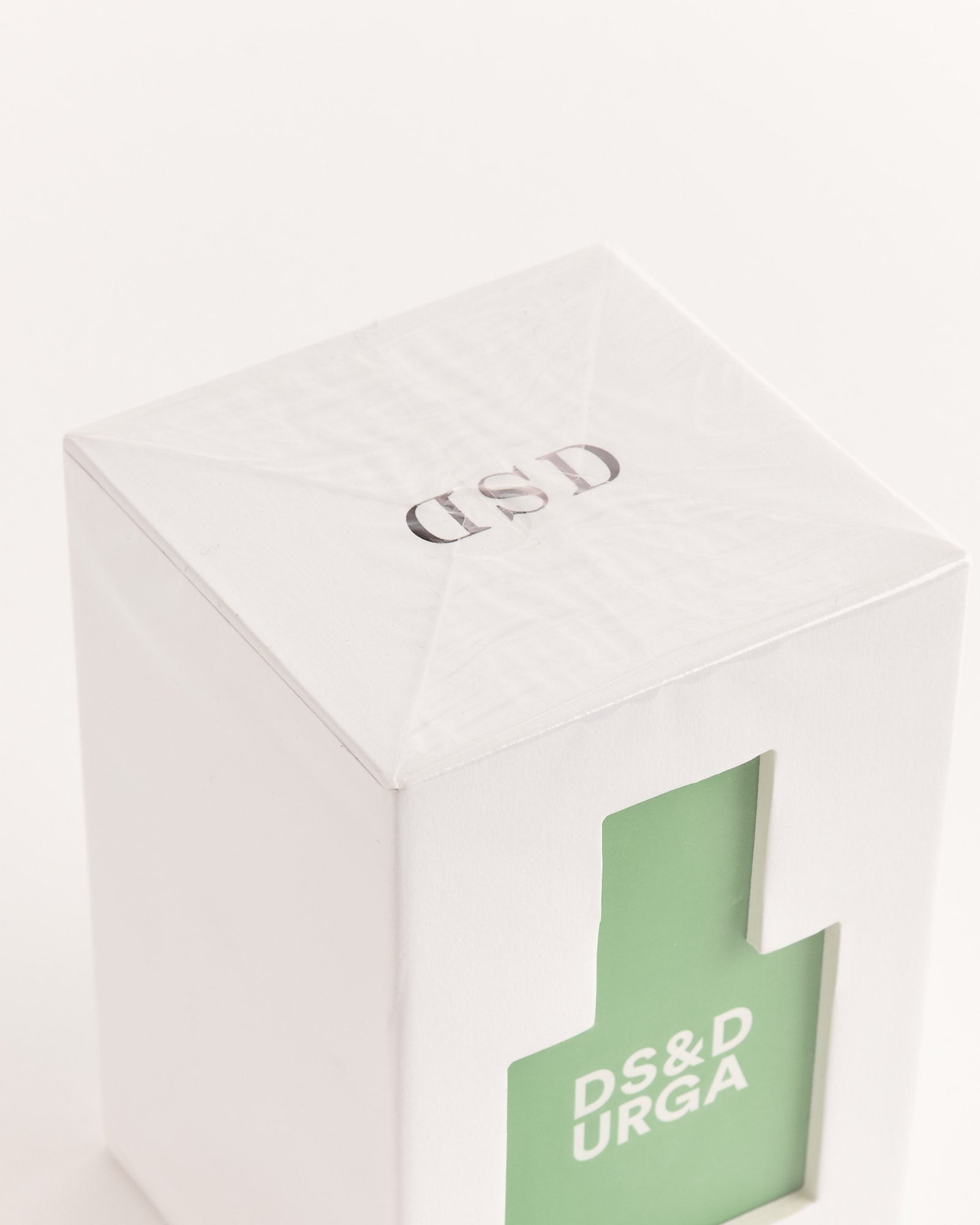 A white box with a cutout shows a green “Crush Balls” label by D.S. & Durga, suggesting vegan perfume. Silver DSD lettering tops the box, while an off-white background highlights its modern, cruelty-free Eau de Parfum aesthetic.