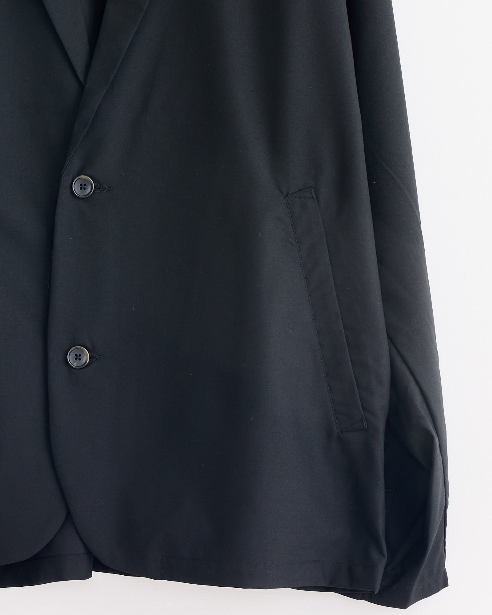 Close-up of the Sillage Veste Tropical Wool Two Button Jacket in Black, featuring two front buttons and a single right-side pocket, displayed against a white background.