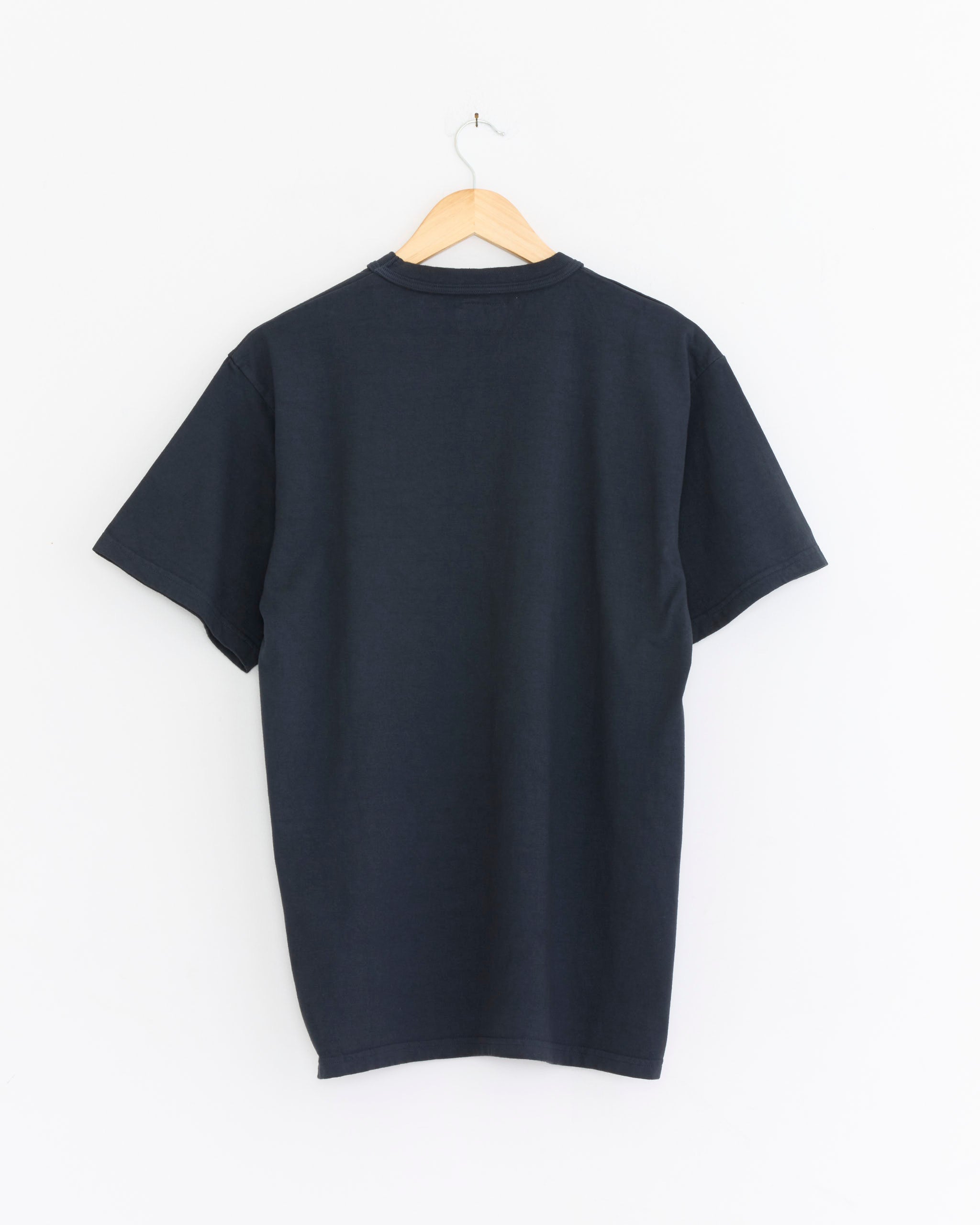 The Sunray Makaha Japanese Jersey T-Shirt in Blue Graphite hangs on a wooden hanger against a white background, displayed from the back with seamless construction.