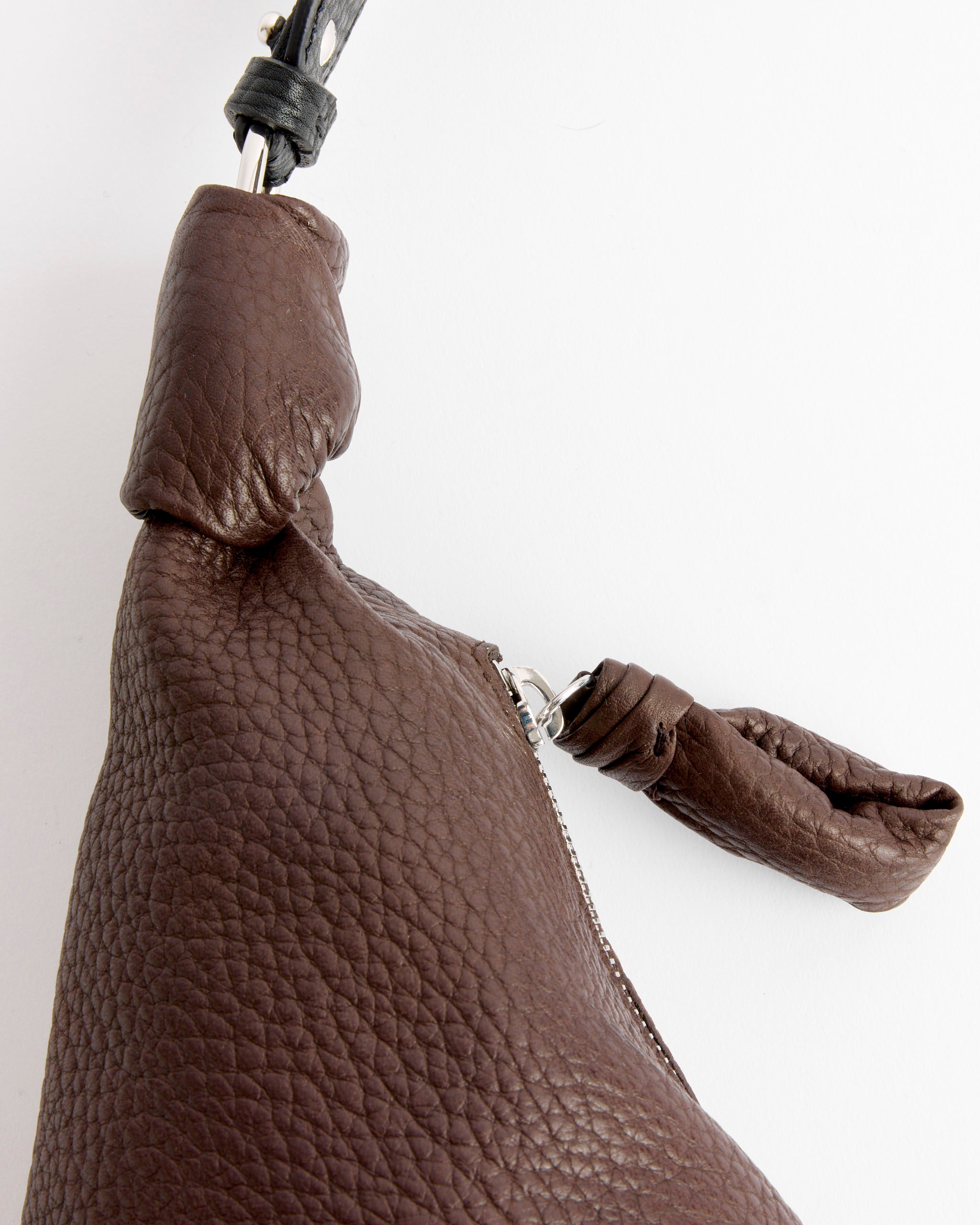 Close-up of Lemaire's Western Studs Medium Croissant Bag in Dark Chocolate, featuring textured cow leather, knotted leather zipper pull and strap, shown against a white background.