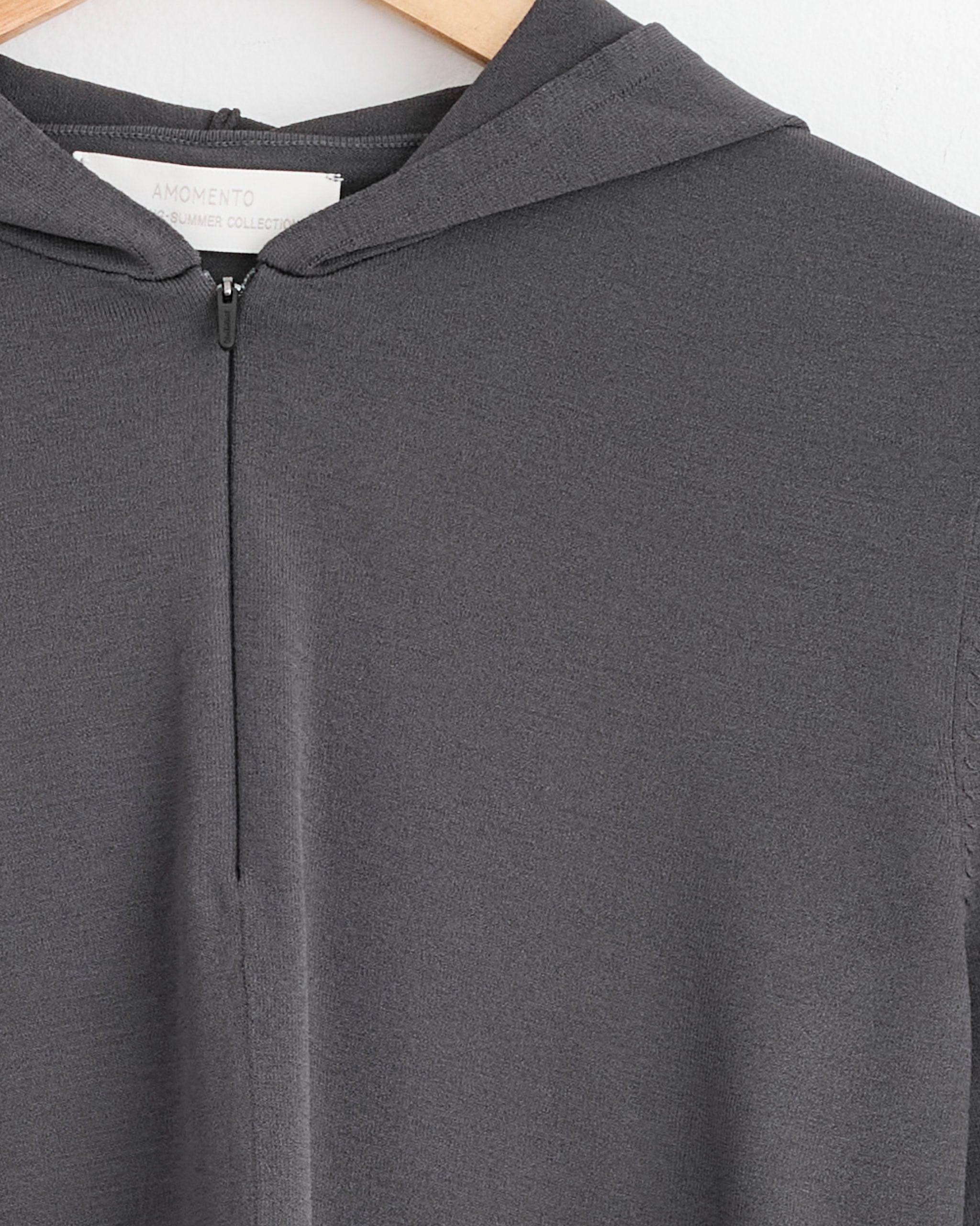 Close-up of the Half Zip-Up Knit Hoodie in Charcoal by Amomento, made from rayon with a central zipper and visible tag. For sizing, please refer to our size chart.
