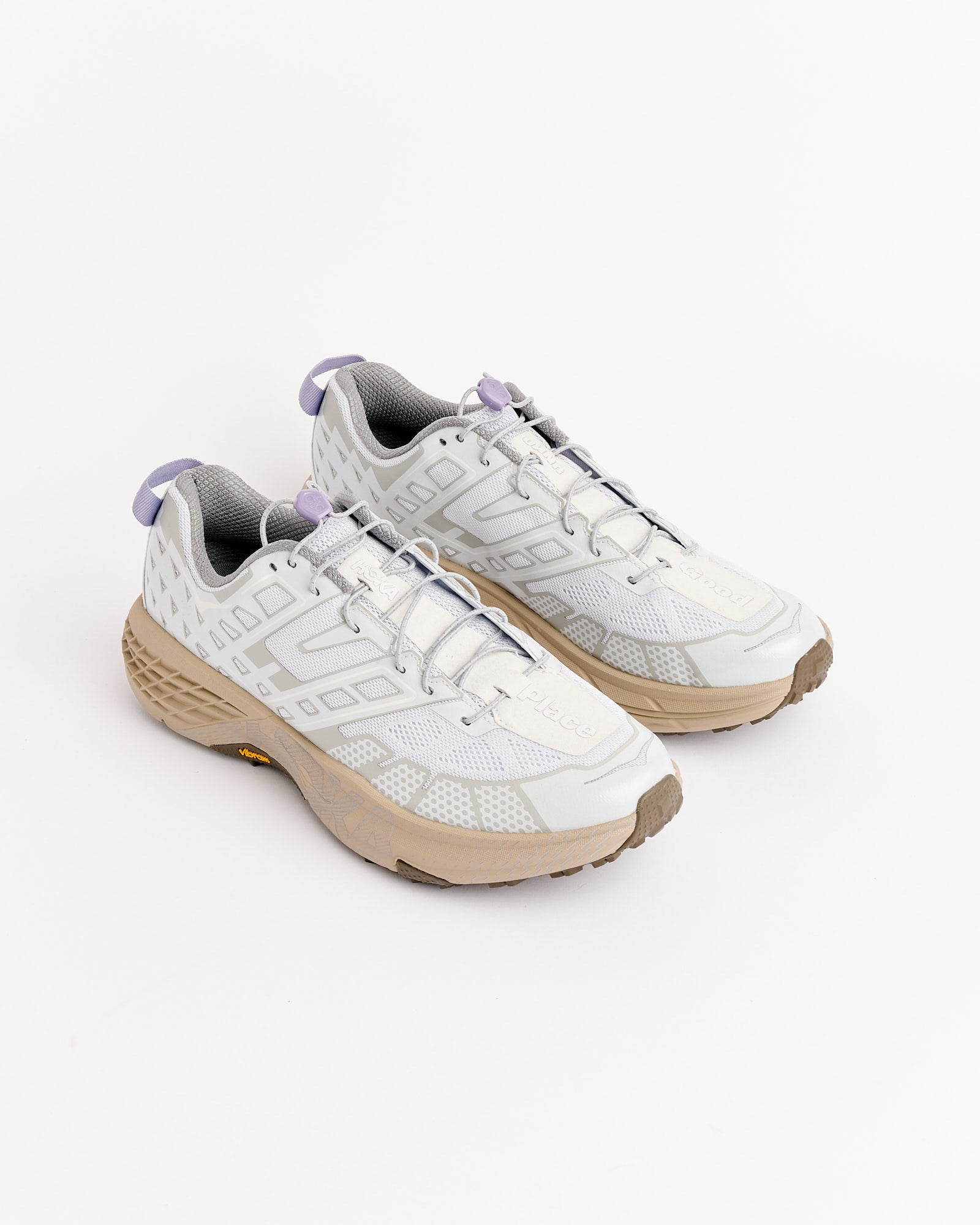 The Hoka SPEEDGOAT 2 UNNA in Sea Ice/Cosmic Grey features white and light gray uppers with beige soles and light purple accents, shown on a white background. Enjoy a perfect fit with all sizing options available.