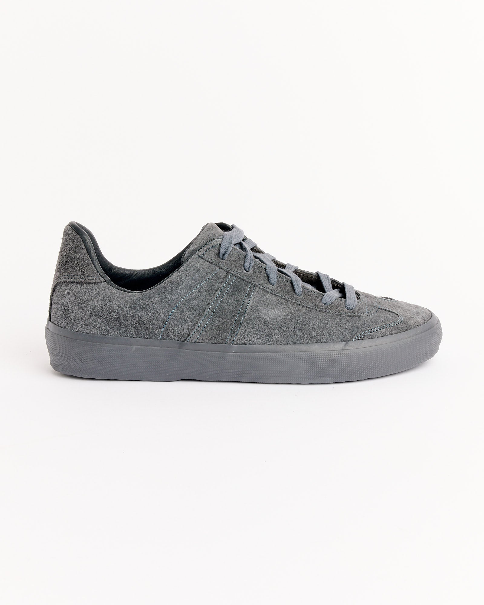 The Still By Hand x Reproduction Of Found Sneakers in Charcoal by Still By Hand are shown in a side profile view, featuring gray suede, gray laces, and a gray rubber sole on a plain white background.