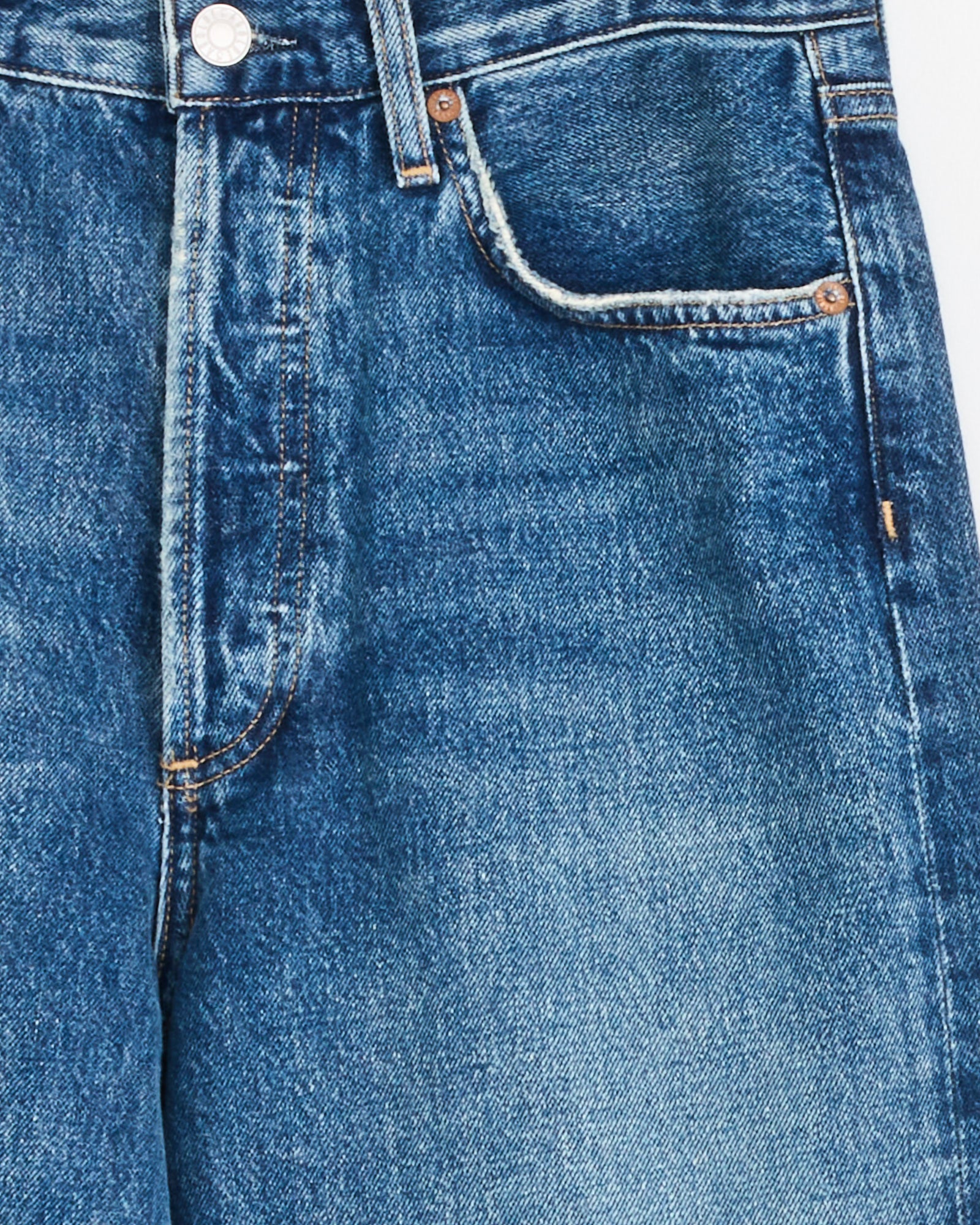 Close-up of the AGOLDE 90s Jean in Bounty, made from regenerative cotton denim. Features include a waistband, front pocket, coin pocket, and metal button—all highlighting its classic '90s style with a softly faded finish.