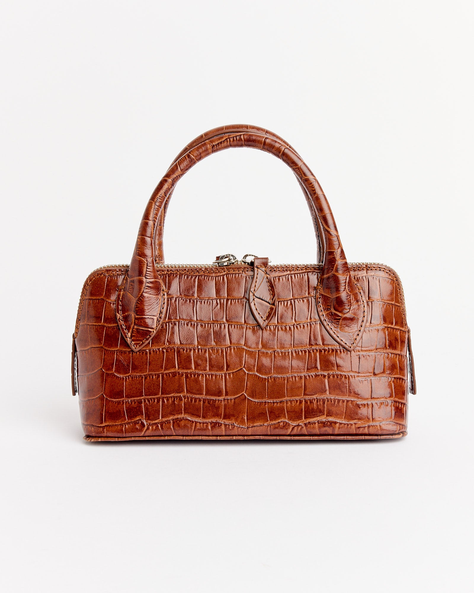 The Cordera Mini Crocodile Bag in Caramel features a crocodile-patterned leather design, rectangular shape, double handles, and zipper closure. Shown on a plain white background. Need sizing help? Chat with us online!.