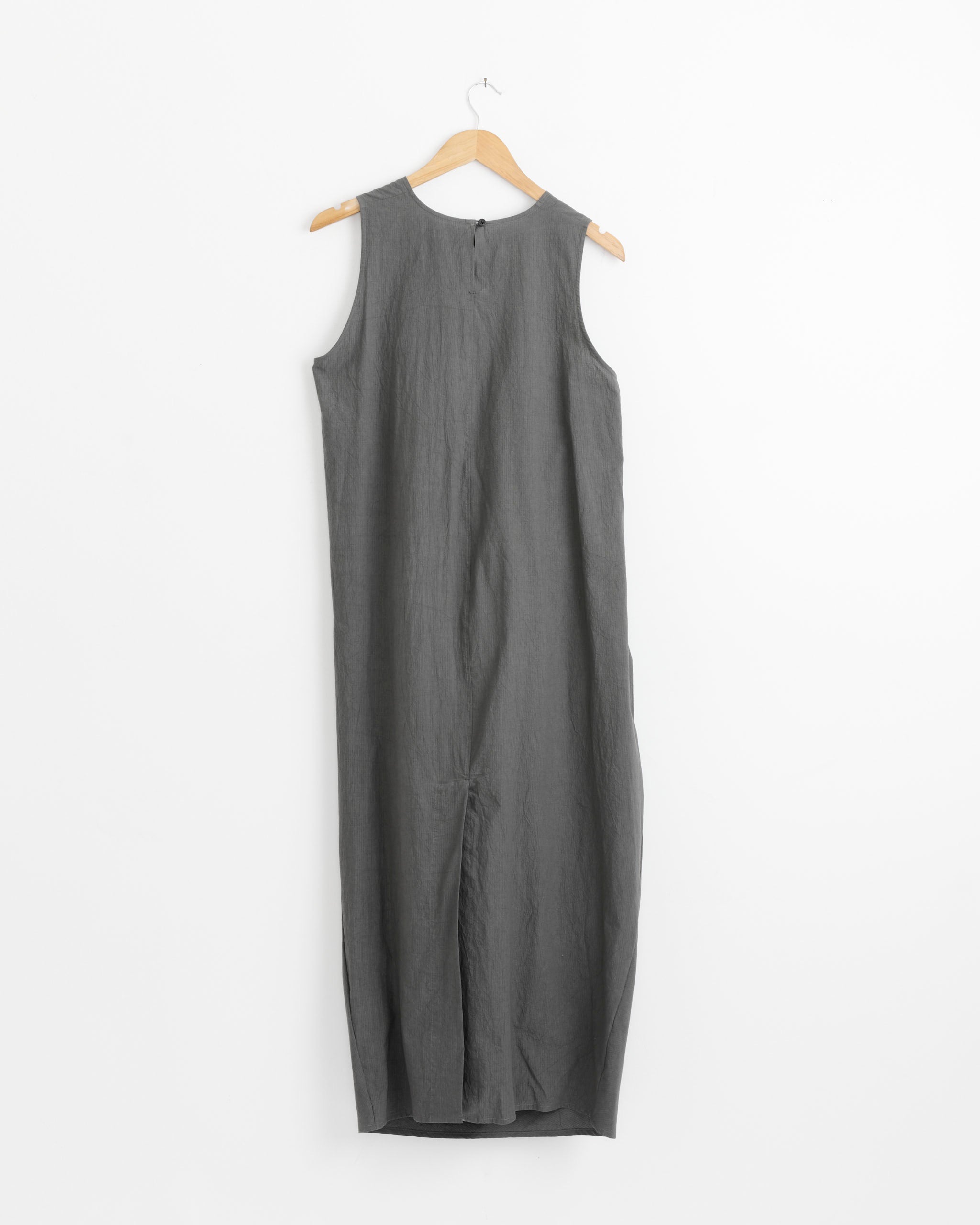 The Ripstop Dress in Coal by Lauren Manoogian is a sleeveless grey cotton midi dress with a round neckline, displayed on a wooden hanger against a white background. Designed for effortless style, it features a loose fit and minimalist look.
