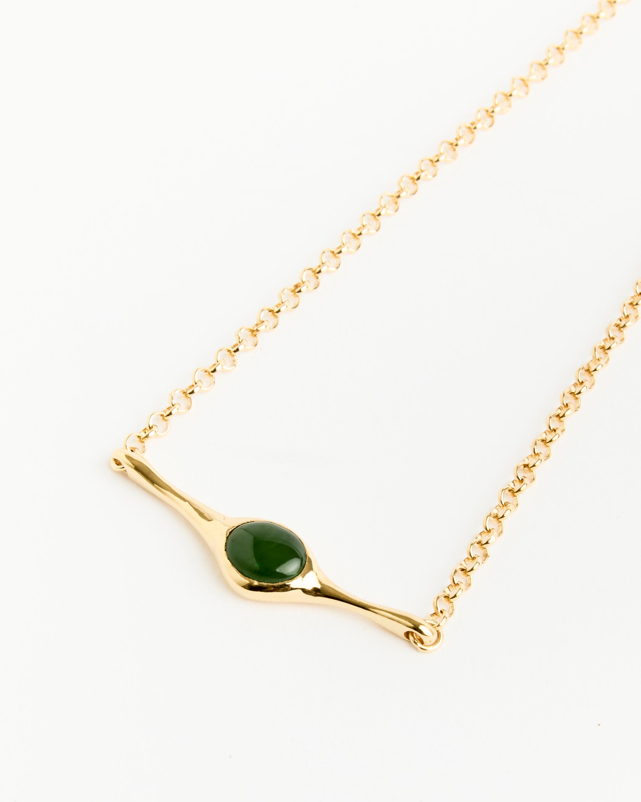 The Faba Necklace by Faris features a gold-plated bronze horizontal bar with a dark green jade pendant at the center, shown against a plain white background.