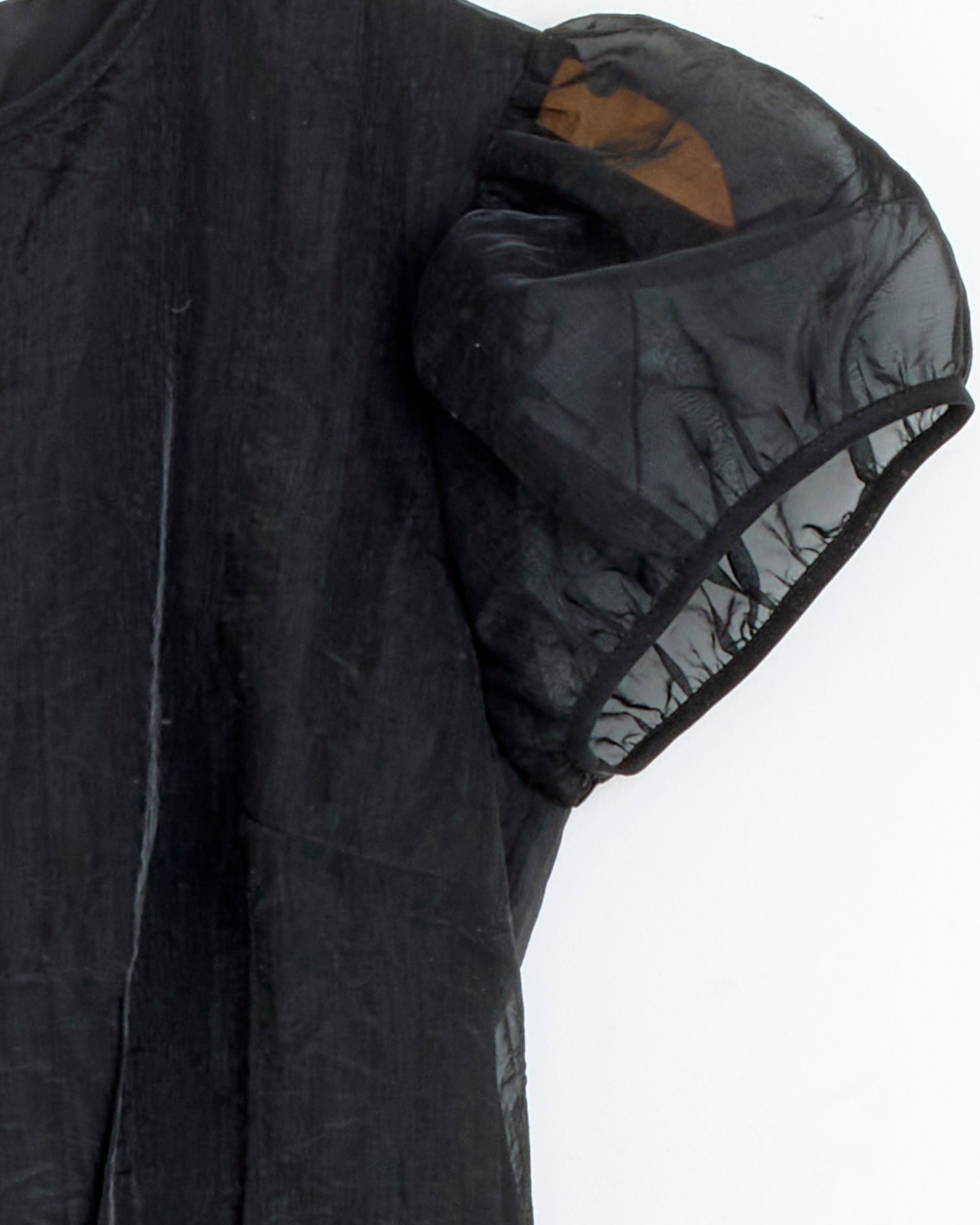 Close-up of Cecilie Bahnsen's Cleopatra Dress in Black Liquid Myrtia, featuring sheer puff sleeves with visible brown shoulder lining, crafted from polyester and displayed against a plain white background.