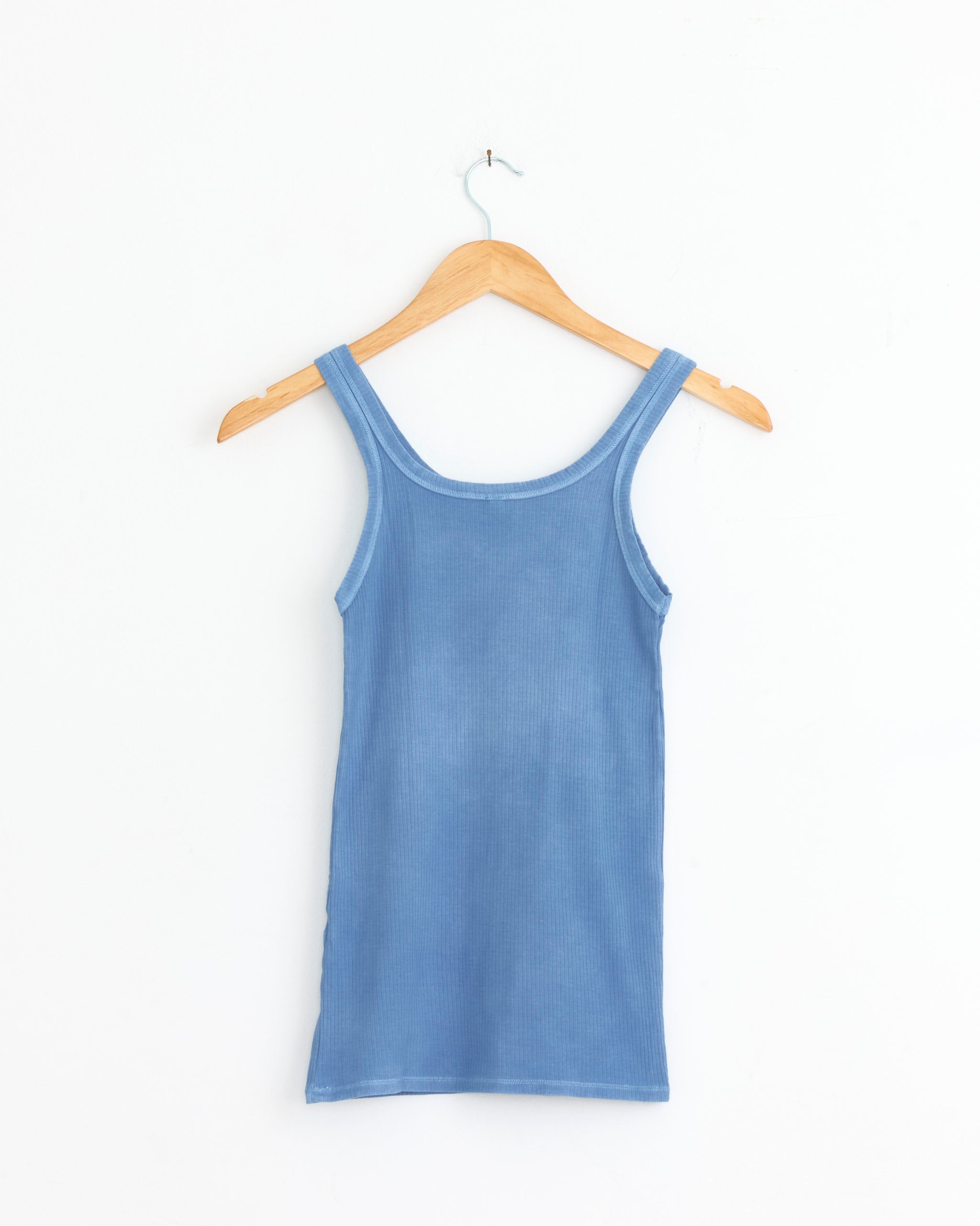 The Heart Tank in Isatis Blue by Baserange hangs on a wooden hanger against a white background—connect with our online chat for any sizing and fit questions.