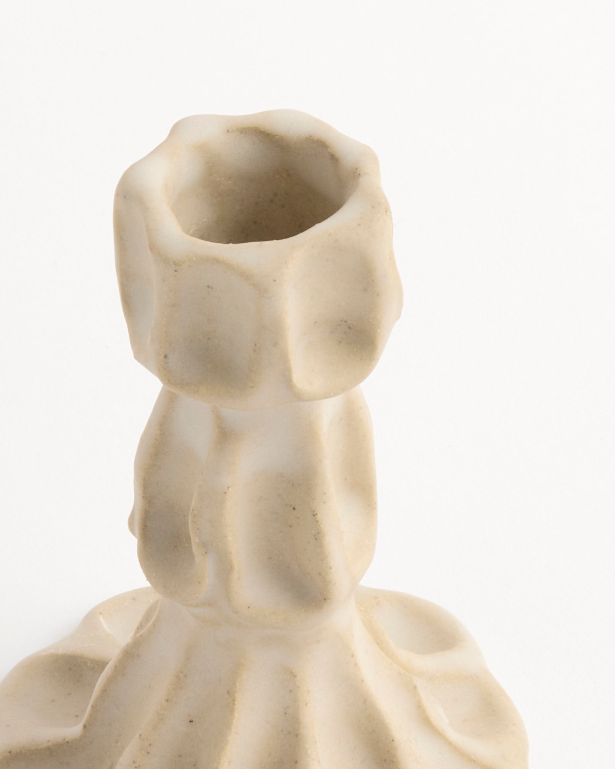 A close-up of the Small Candle Stick by Carma Ferrier Ceramics, showcasing its beige, textured handmade ceramic and organic sculpted design, set against a plain white background.