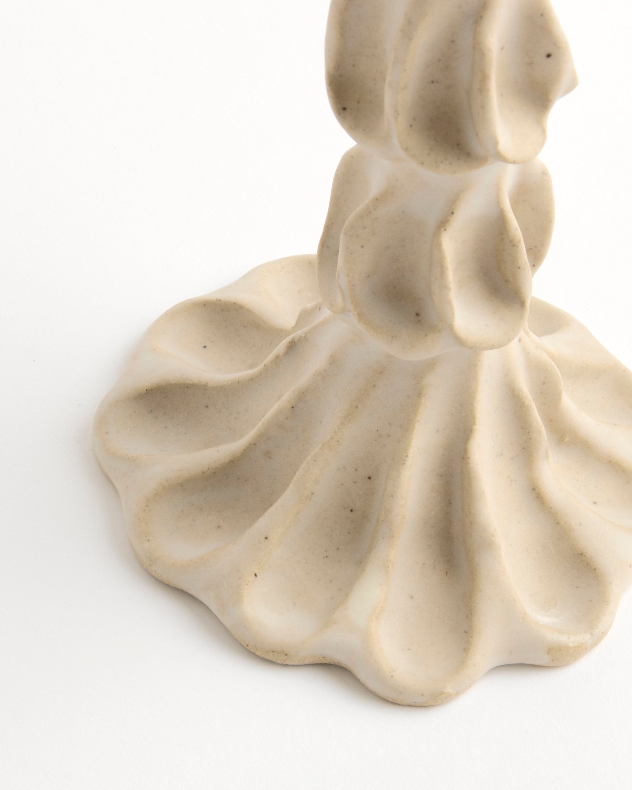 A close-up of the Large Candle Stick by Carma Ferrier Ceramics features its beige, wavy ceramic base with a textured, organic design against a white background.