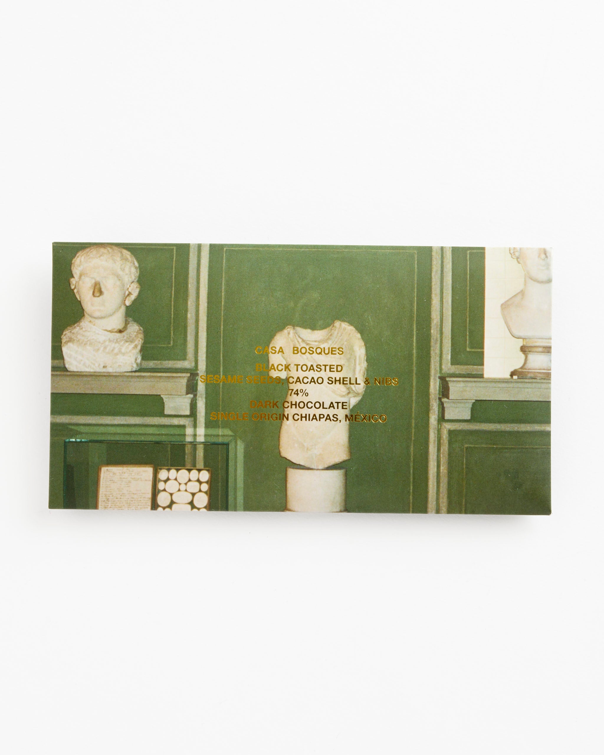 The Casa Bosques Black Toasted Sesame / Cacao Shell & Nibs Chocolate bar comes in a green organic wrapper with gold text and a photo of classical white busts and sculptures on green shelves.