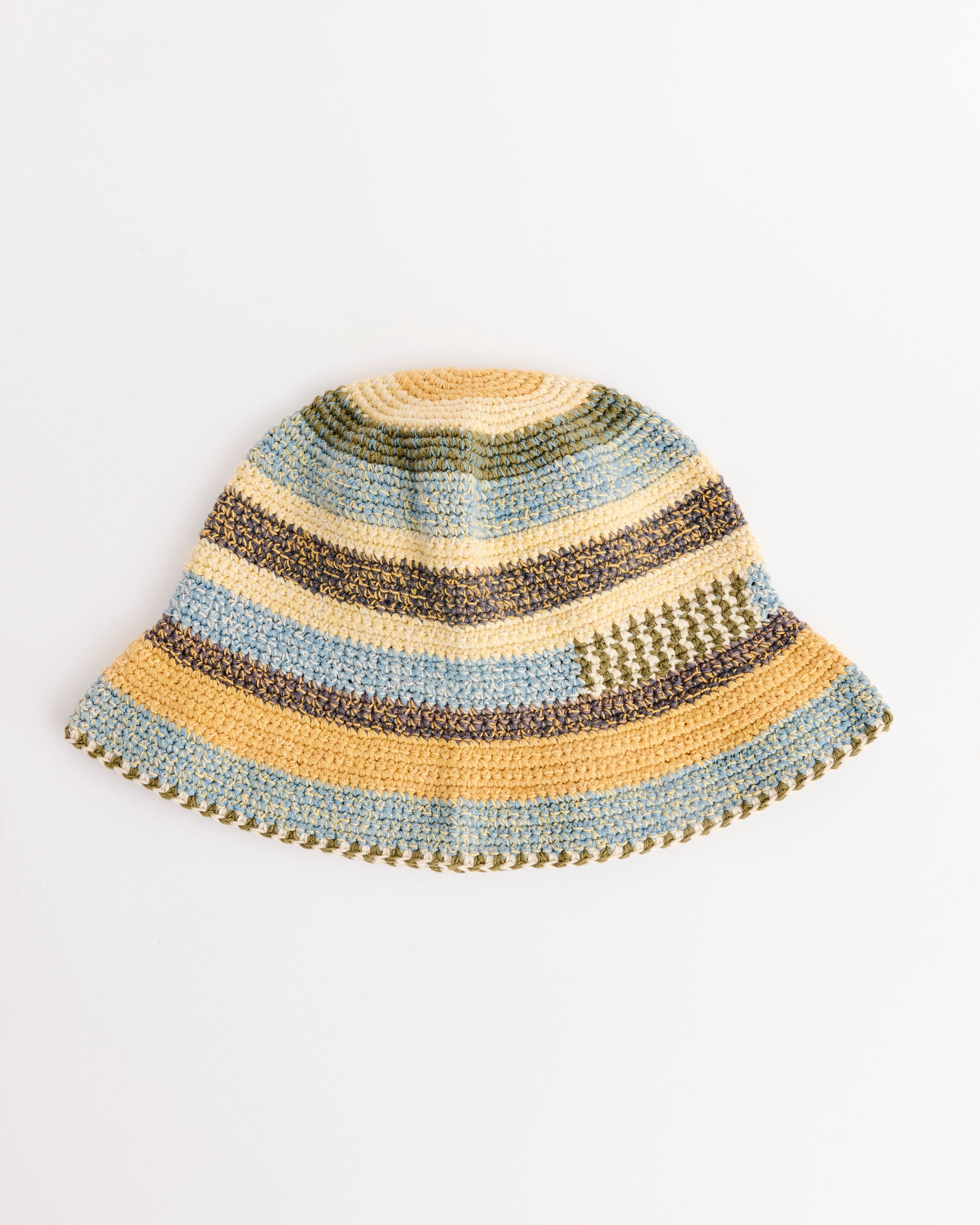 The Story mfg Brew Hat in Twisted Stripe is hand-crocheted from organic cotton, naturally dyed, and features horizontal yellow, green, blue, and beige stripes on a white background.