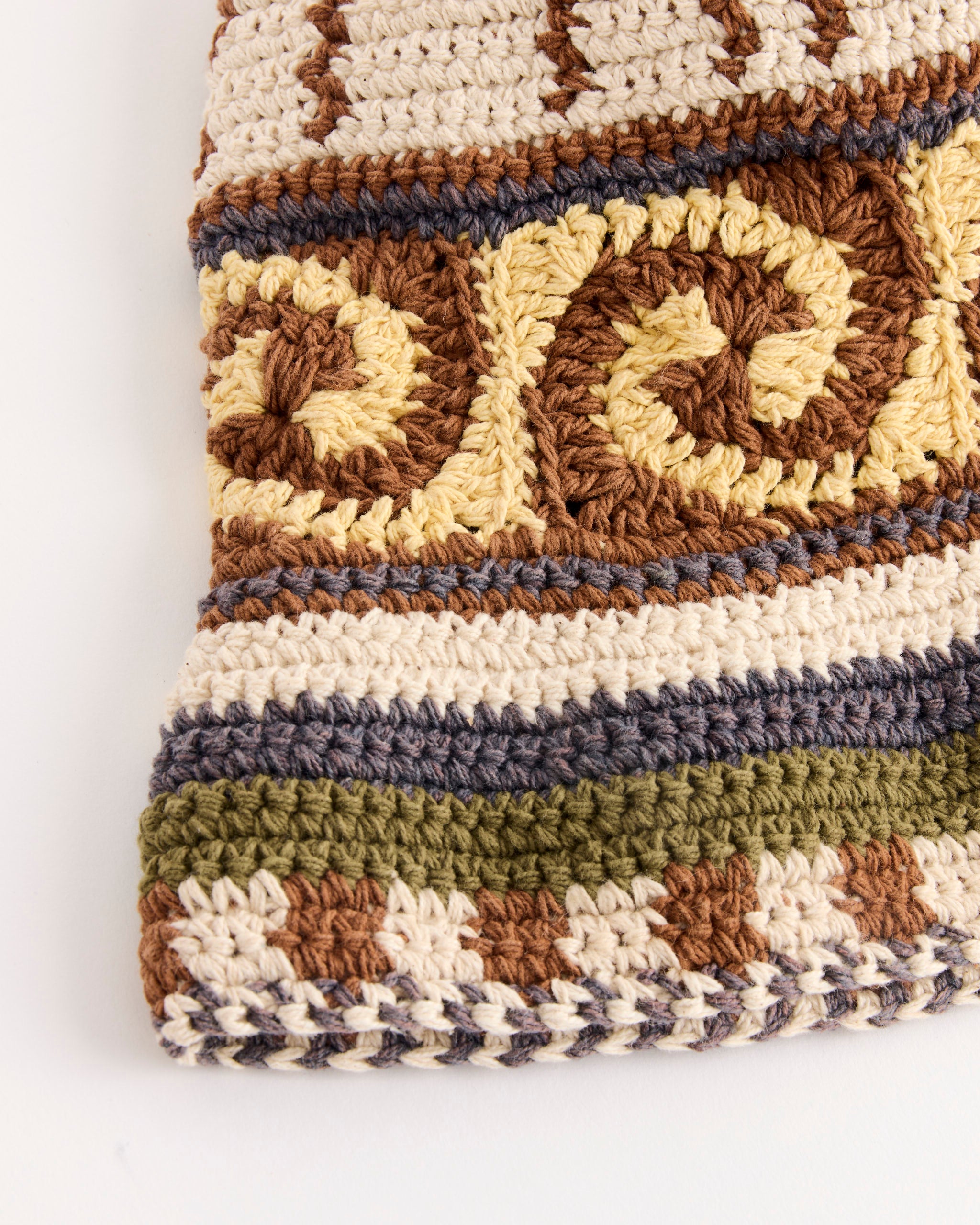 Close-up of knitted fabric with intricate swirling and geometric patterns in earthy tones, reminiscent of the Story mfg Brew Hat in Olive Spiral—an artfully crafted organic cotton accessory.