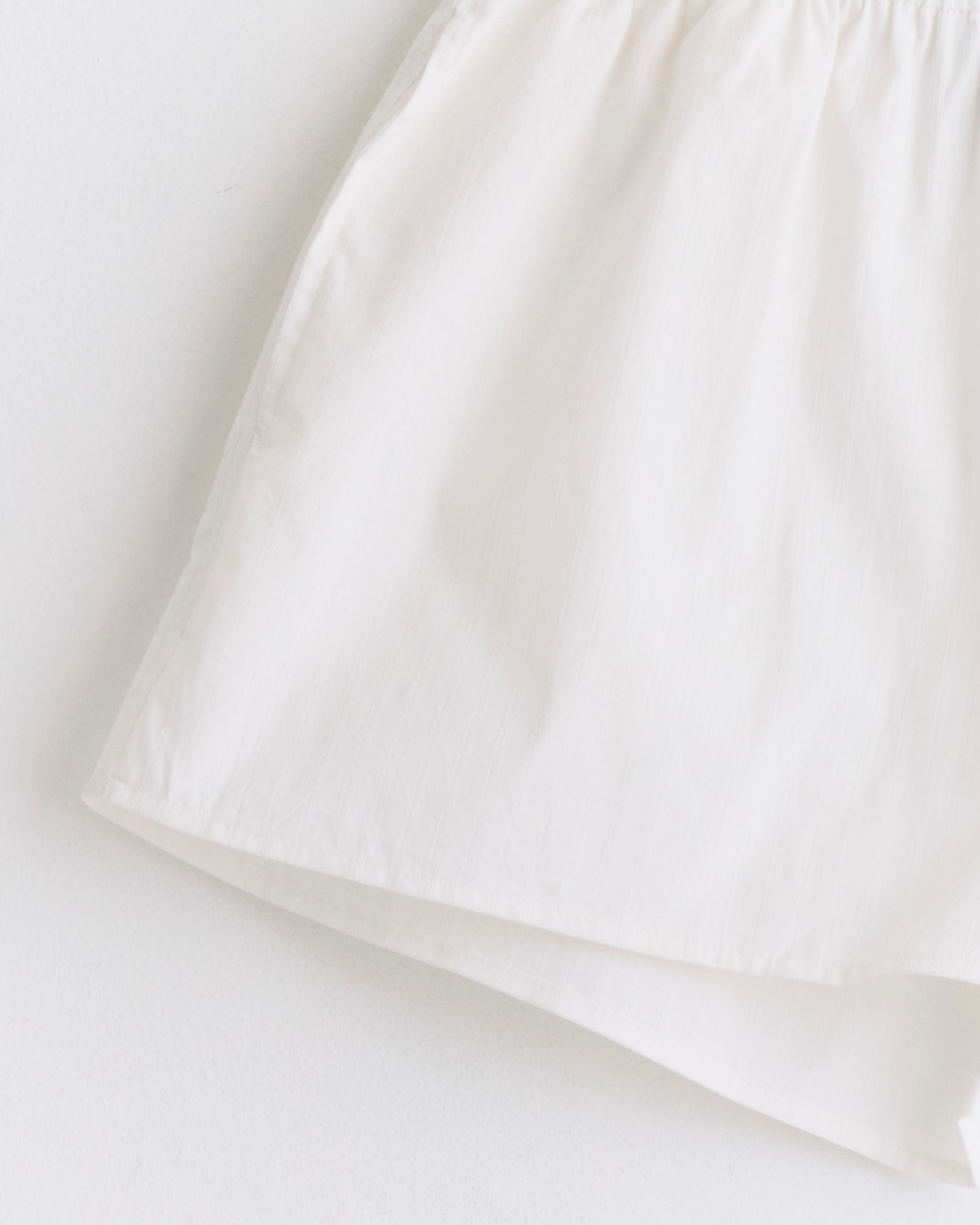 A close-up of Deiji Studios’ Round Collar Set in White Texture, featuring lightweight organic cotton shorts with an elastic waistband, shown against a plain white background.
