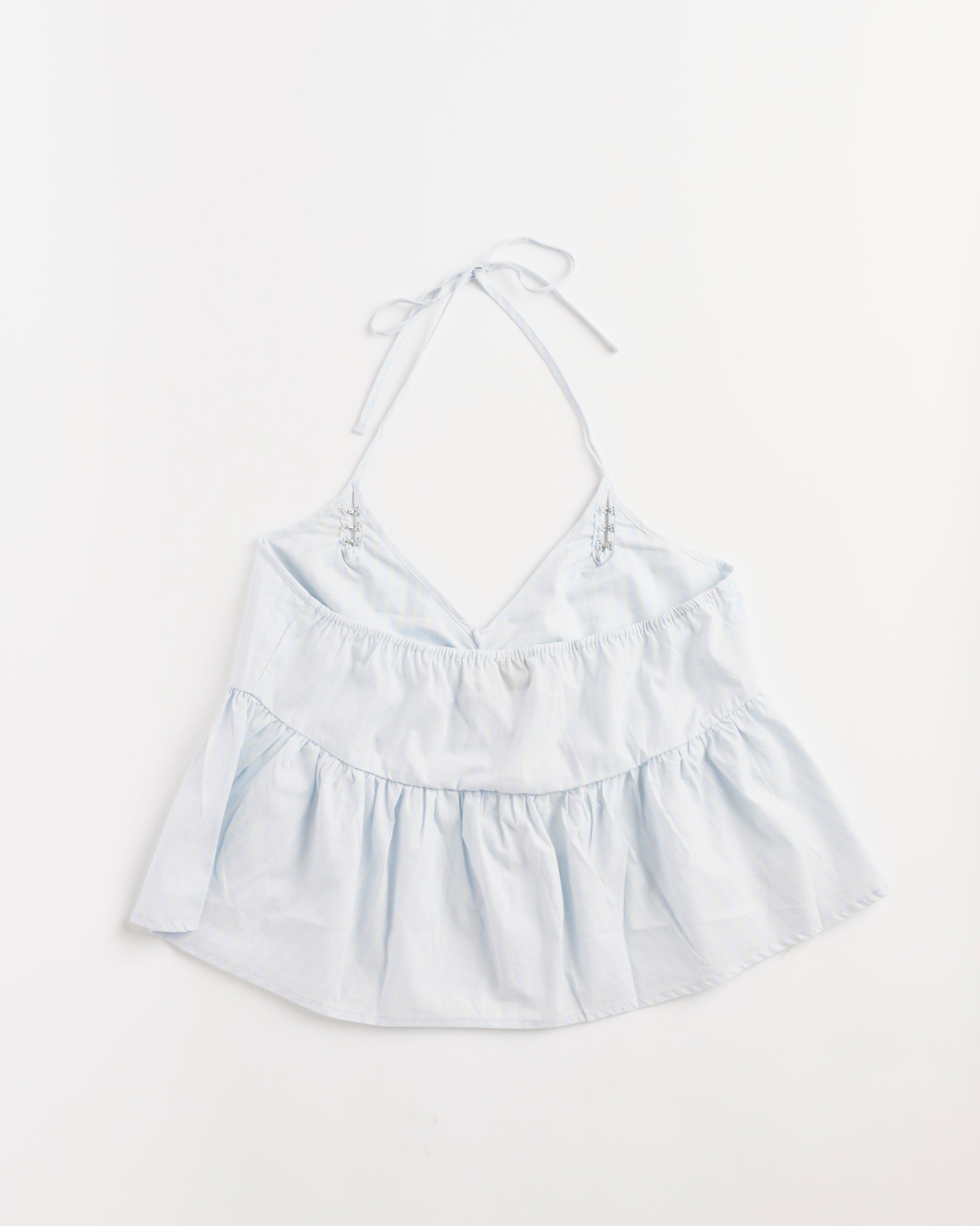 Deiji Studios Keyhole Halter Top in Powder Blue Stripe, sleeveless with a V-neckline and gathered ruffled hem, shown laid flat on a white background.