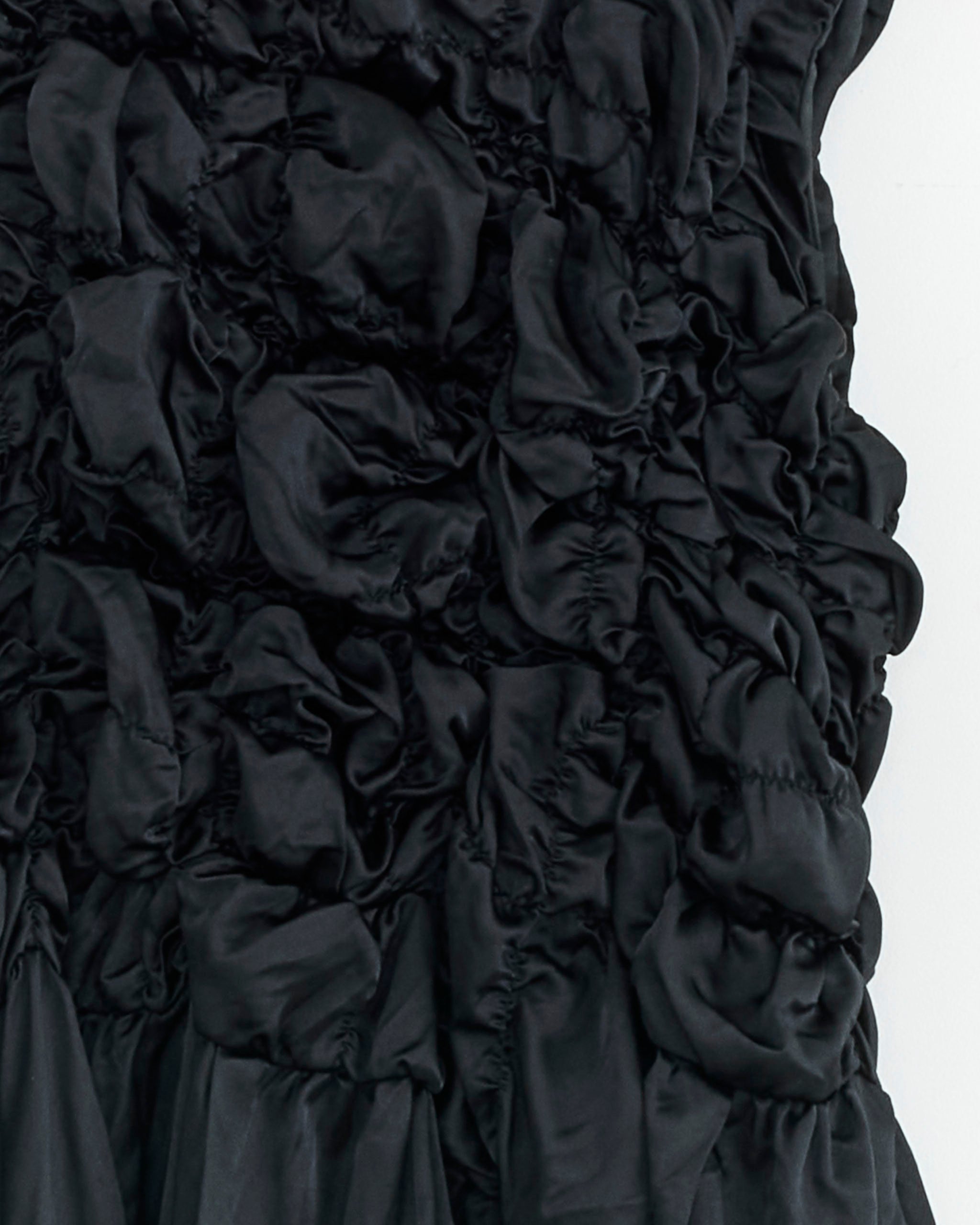 Close-up of navy ruched fabric from the A001 Dress by Comme des Garçons Comme des Garçons, crafted in Japanese polyester with a gathered texture that forms a striking three-dimensional pattern.
