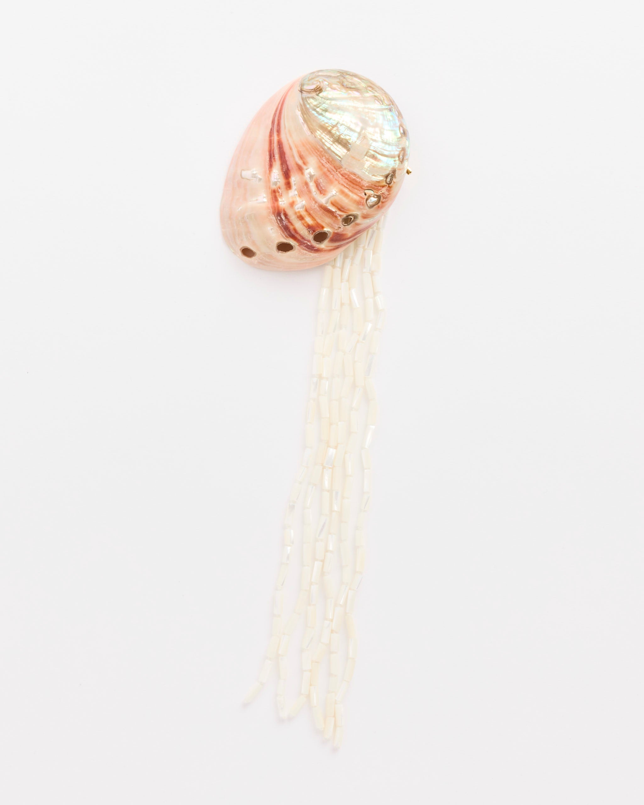 The Abalone Brooch by Mosquito features a pink, iridescent seashell with holes atop long white beaded strands, resembling a jellyfish—perfect for sparking online conversation about style or fit.