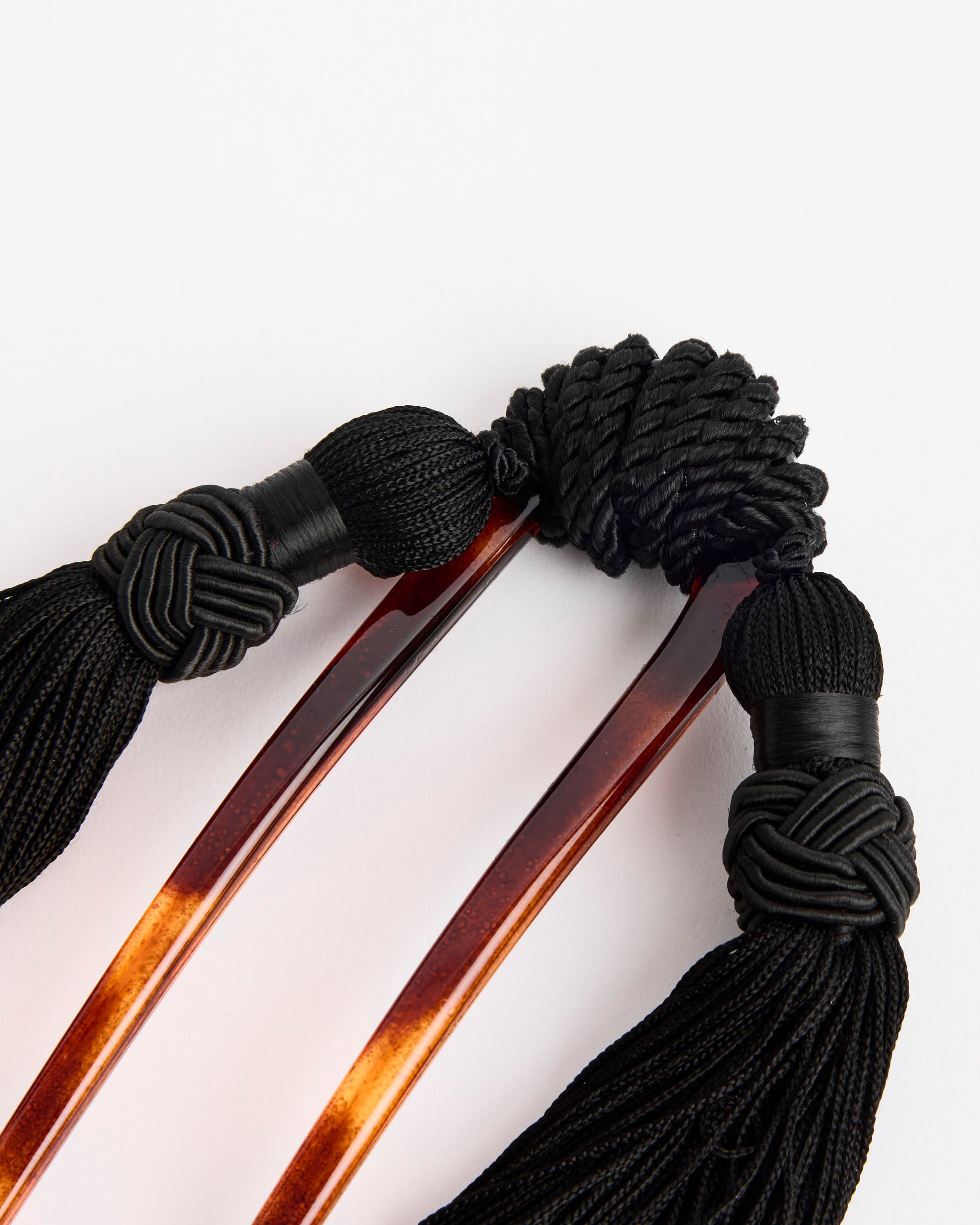 The Mosquito Vega Hair Comb with Silk Tassels features stylish brown tortoiseshell and decorative tassels, perfect for customizing your look. Questions about sizing? Contact us via online chat for help.