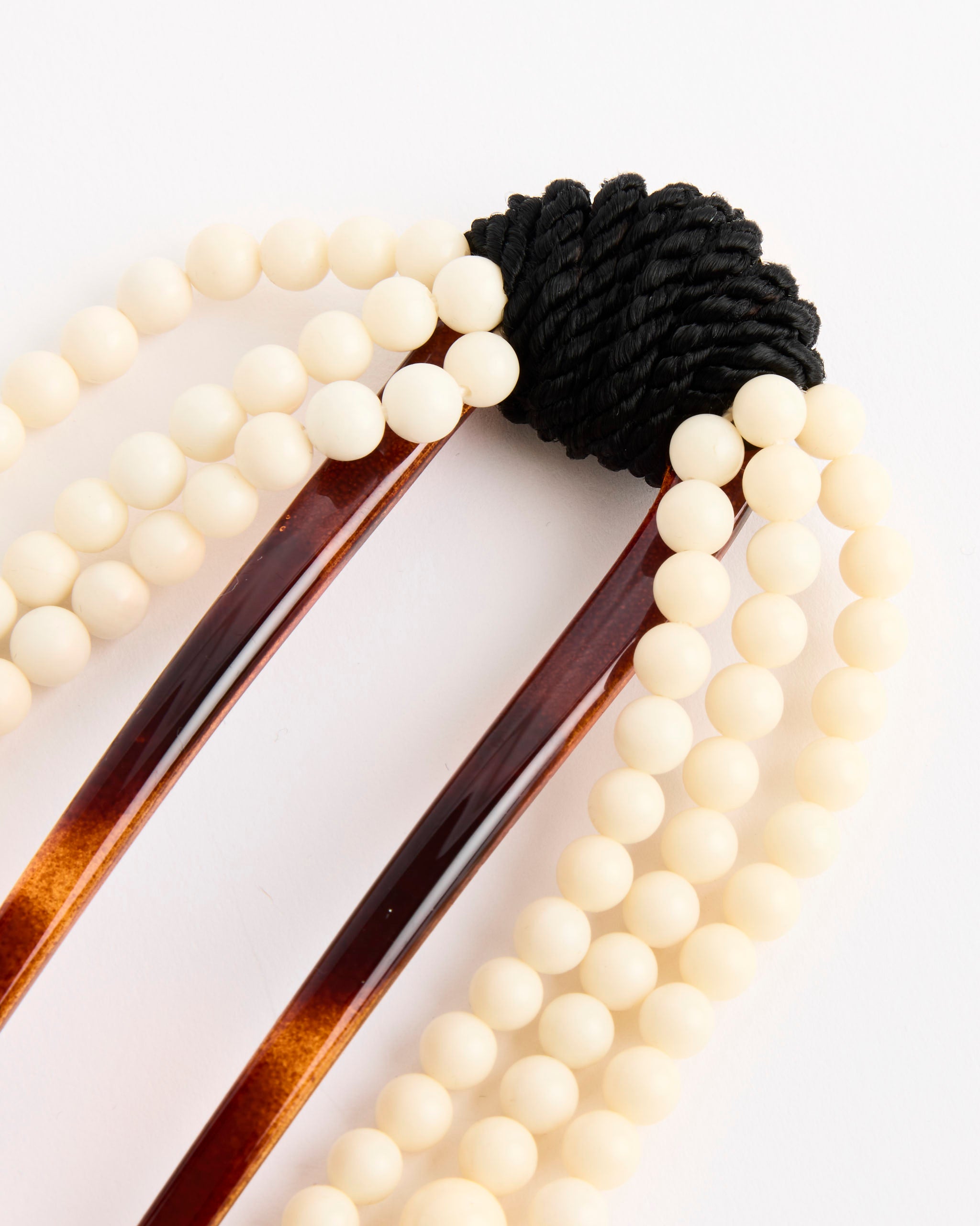 The Mosquito Cande Hair Comb features a brown fork with cream-colored beads and black cord detail, shown on a white background. Online chat is available for sizing and fit questions.