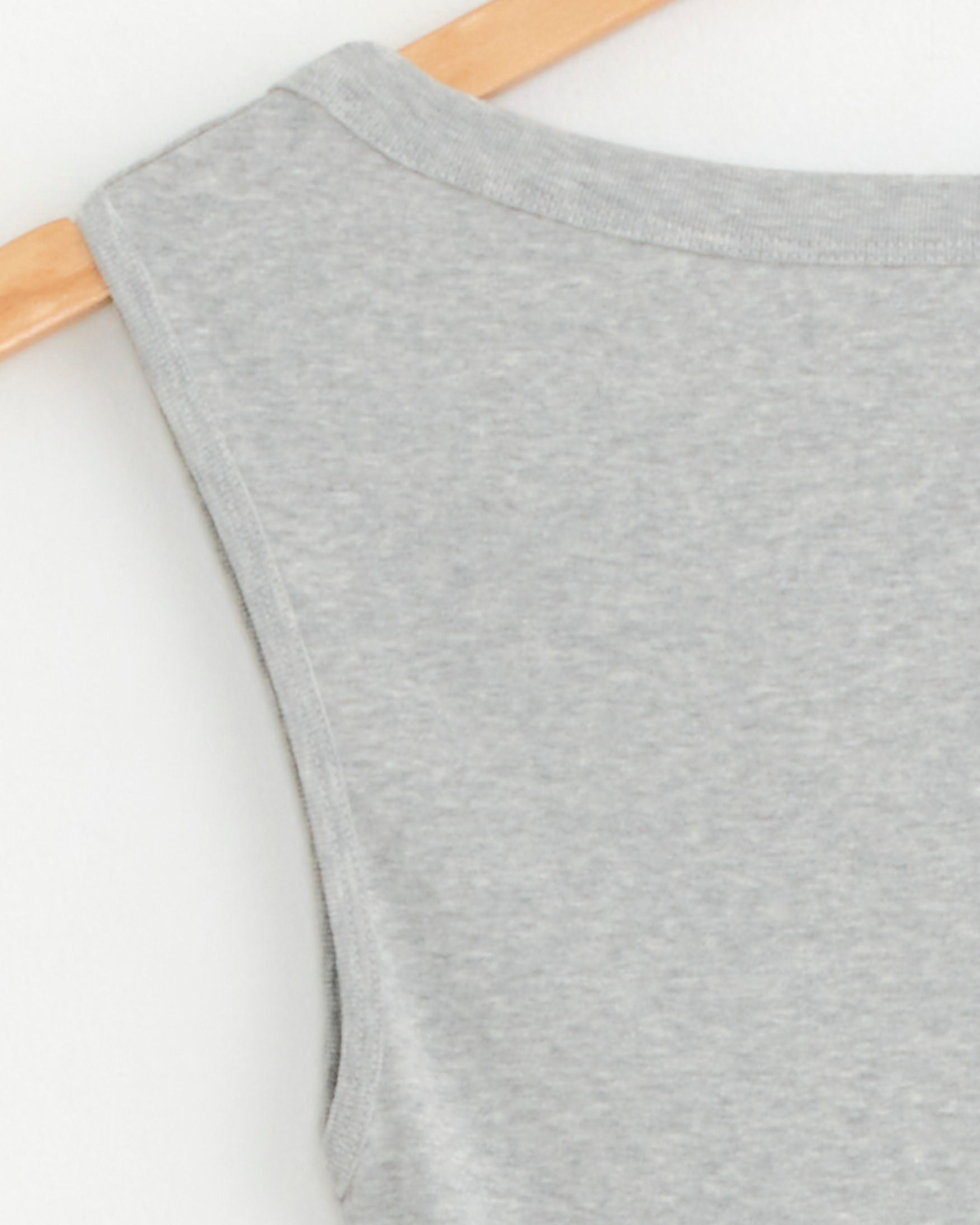 Close-up of the upper back of the ST. AGNI Ballerina Top in Light Grey Marle, crafted from organic cotton and shown sleeveless on a wooden hanger against a white background.
