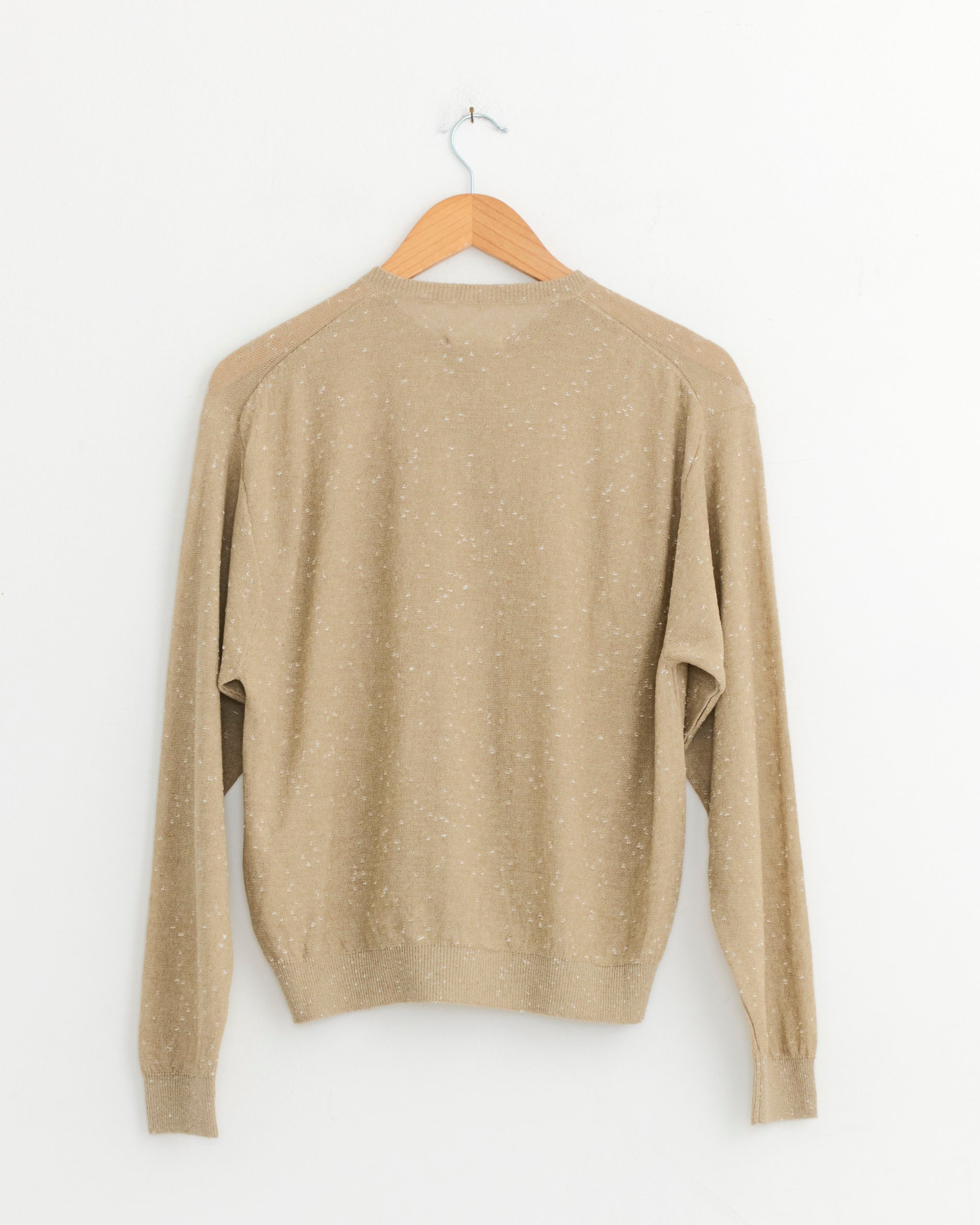 The CORDERA Flecked Cardigan in Beige, made from a linen-cotton blend with long sleeves, is displayed from the back on a wooden hanger against a plain white wall.