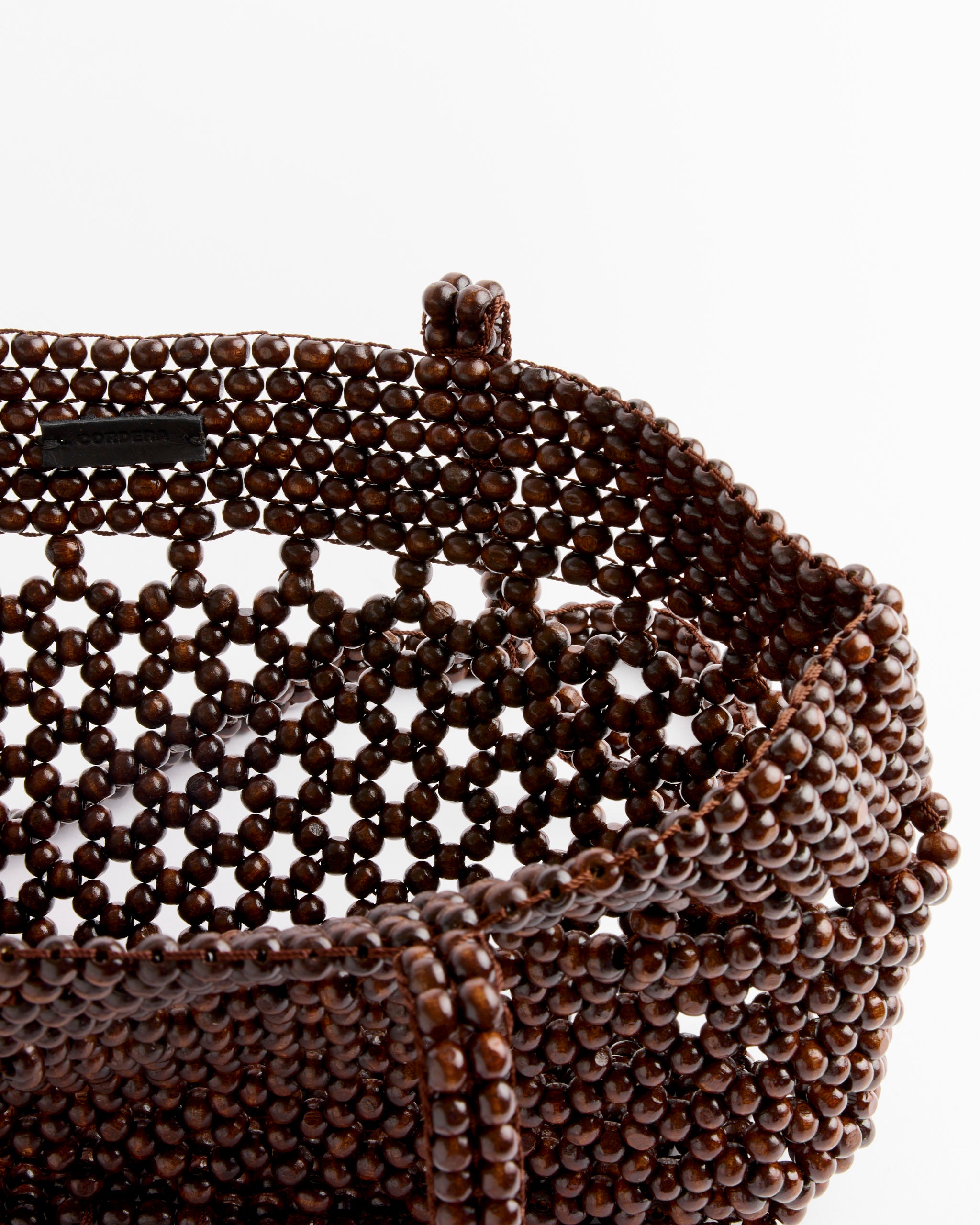 Close-up of the CORDERA Wooden Beads Mini Bag in Brown, showcasing its woven open pattern and artisanal craftsmanship with round wooden beads, revealing the interior against a white background.