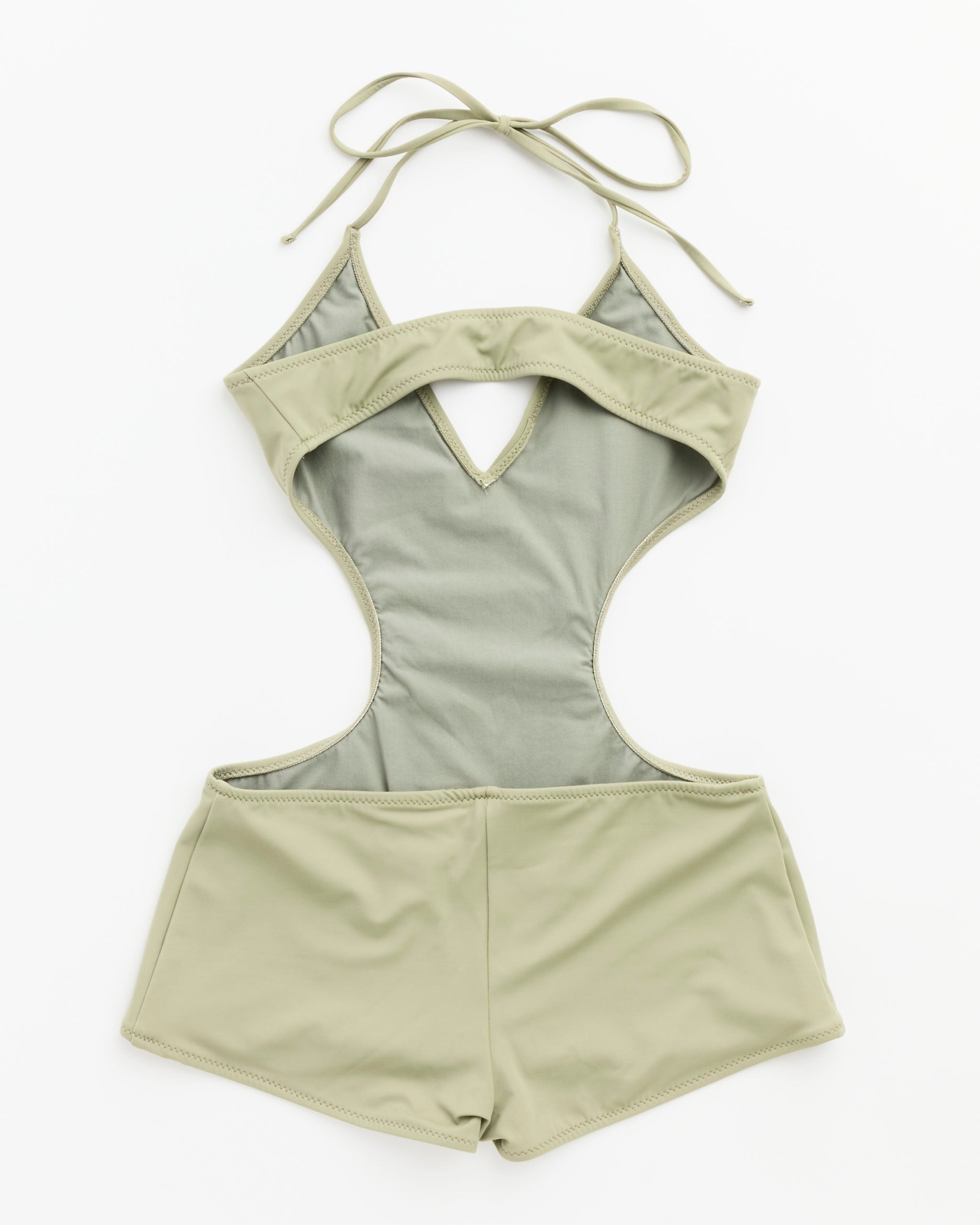 The Paloma Wool Sole Swimsuit in Turquoise is made from recycled polyamide and elastane. It features high-waisted shorts, a halter neck tie, cutout under the bust, and open sides—designed in España and shown on a white background.
