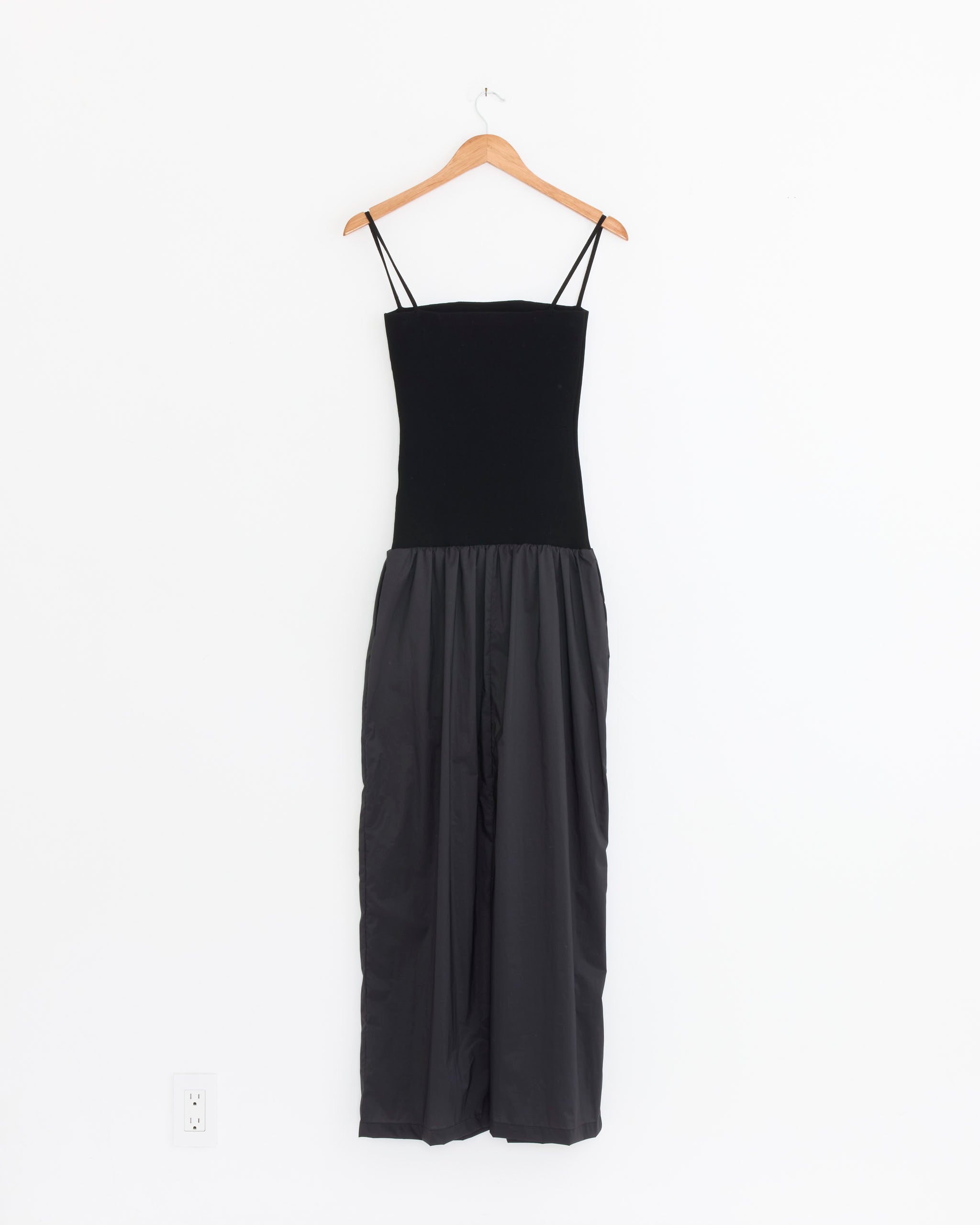 The Amomento Nylon Jersey Maxi Dress in Charcoal features thin straps, a fitted bodice, and a loose, floor-length skirt for effortless elegance. Shown on a wooden hanger against a plain white wall.