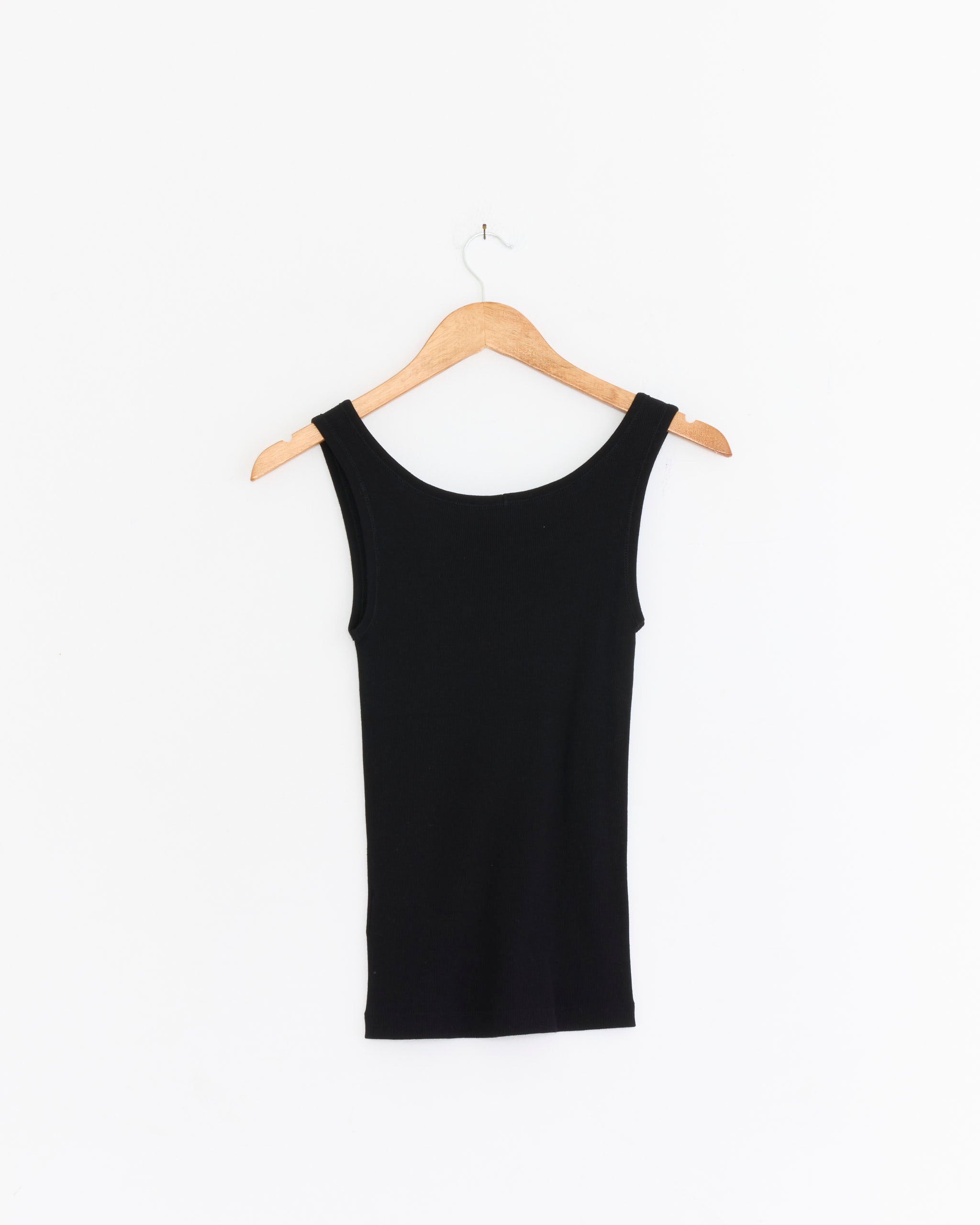 A Comoli Ribbed Tank Top in Black hangs on a wooden hanger against a plain white background.