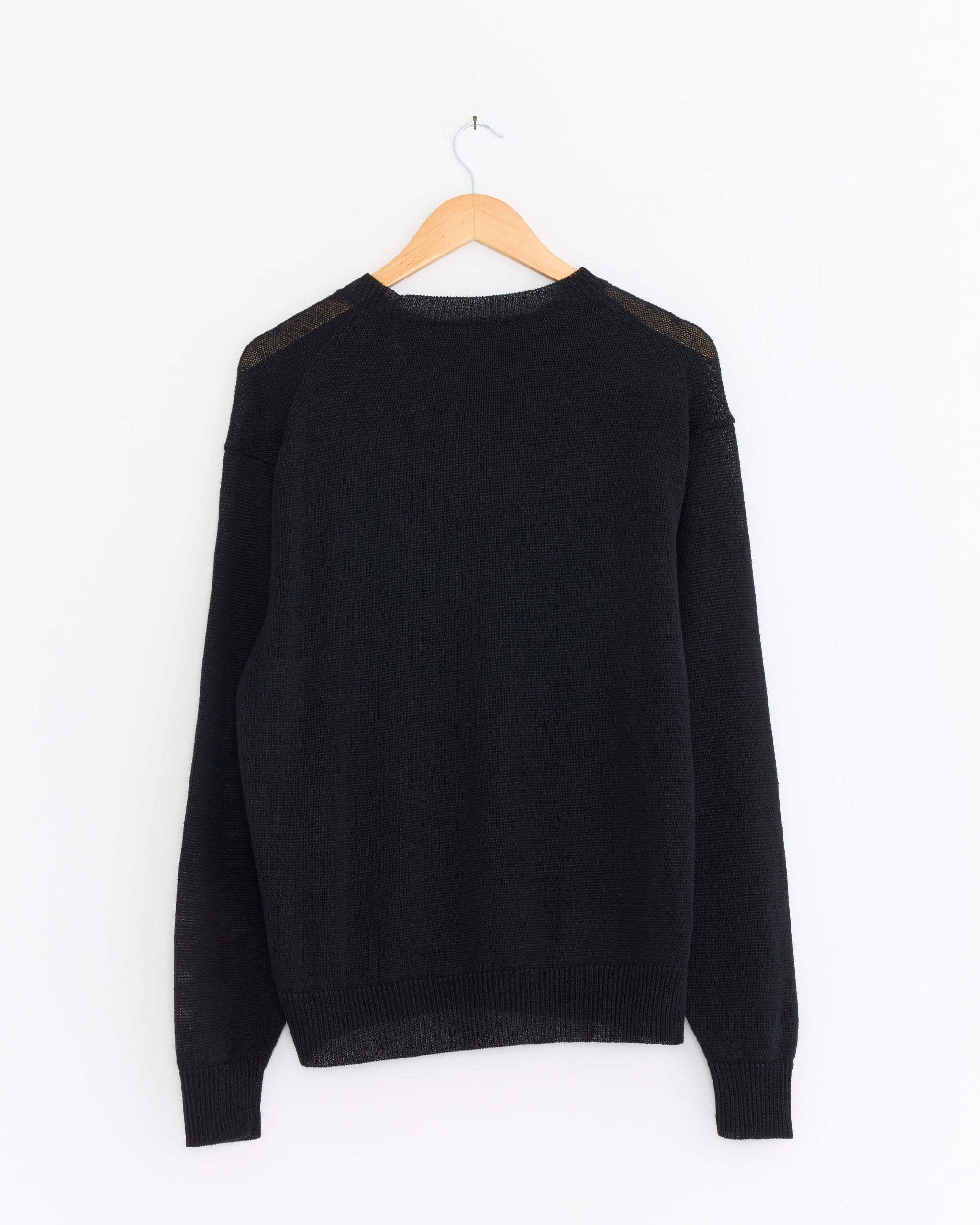 The Comoli Linen Crewneck Knit Pullover in Black hangs on a wooden hanger against a white background.