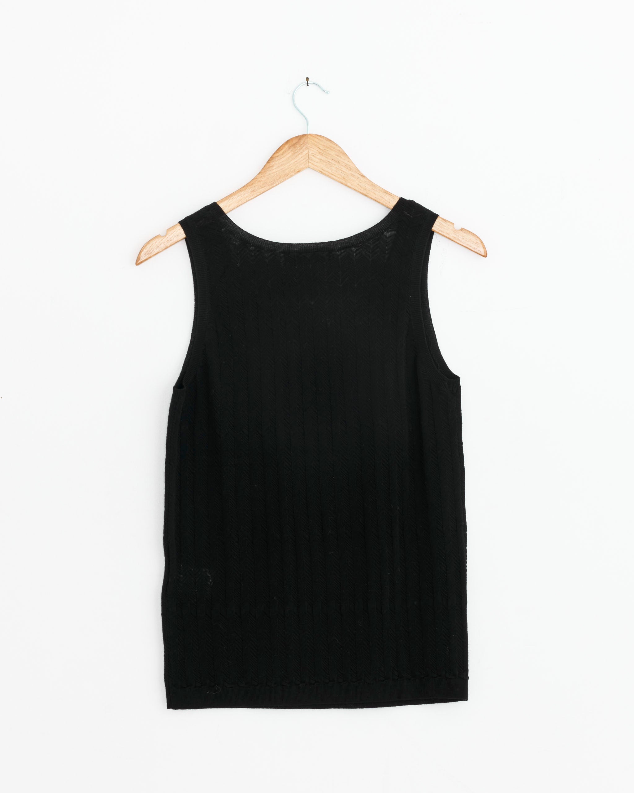 The Dries Van Noten Knit Tank Top in Black, crafted in Belgium from 100% cotton, hangs on a wooden hanger against a white background. This sleeveless top features a round neckline and a simple, straight-cut design.