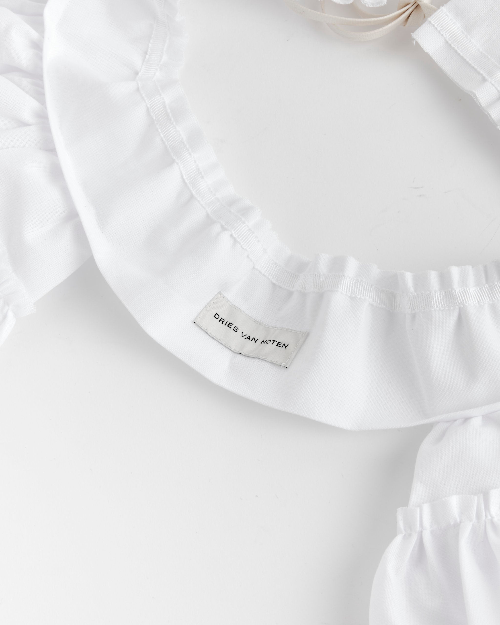 Close-up of the Dries Van Noten Ruffled Belt in White with label visible against a plain background—ideal for those seeking fit or sizing details via online chat.