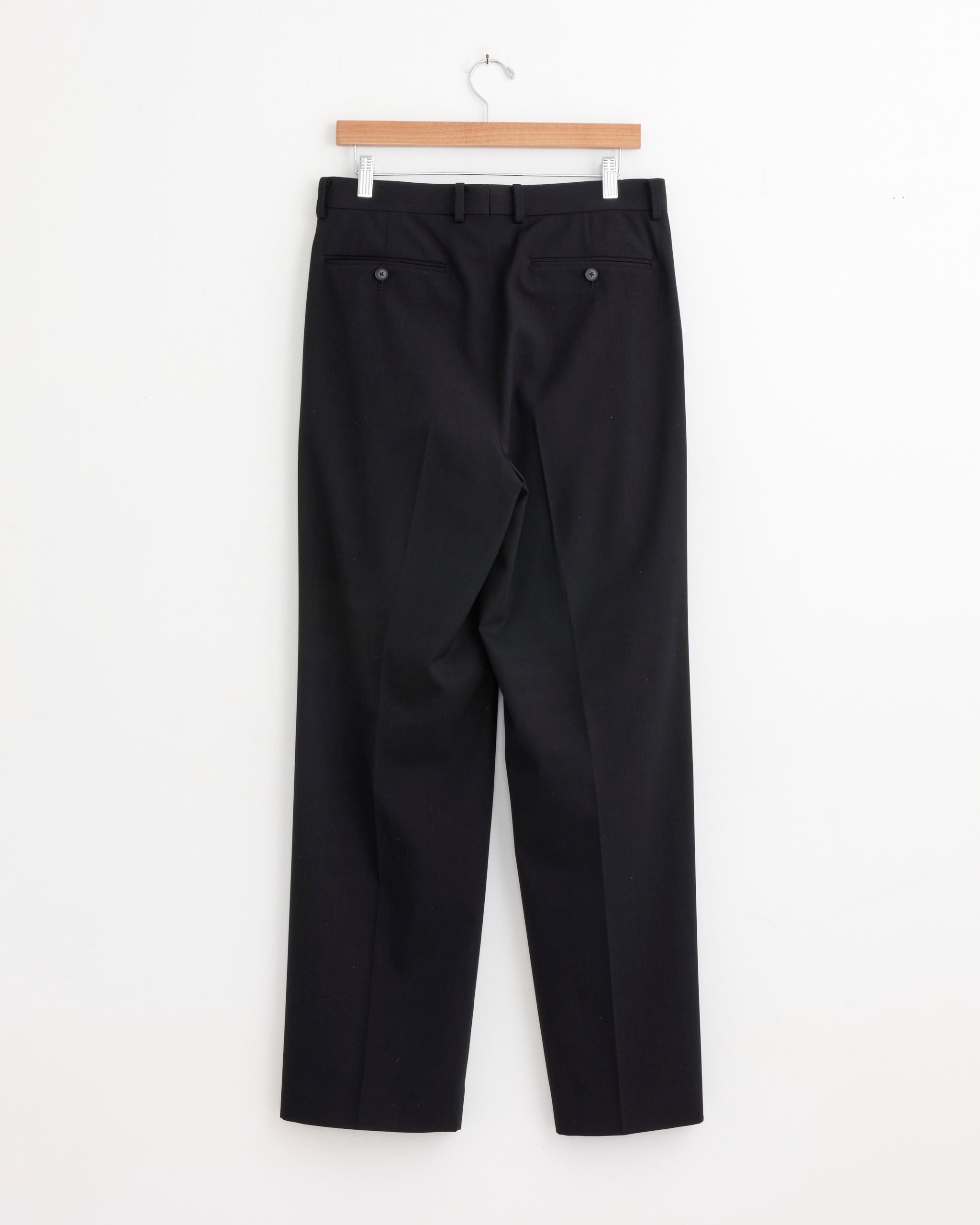 The Auralee Light Wool Max Gabardine Two Tuck Slack in Top Black, shown from the back with belt loops and buttoned back pockets, features a straight-leg cut and wrinkle-resistant wool, made in Japan.