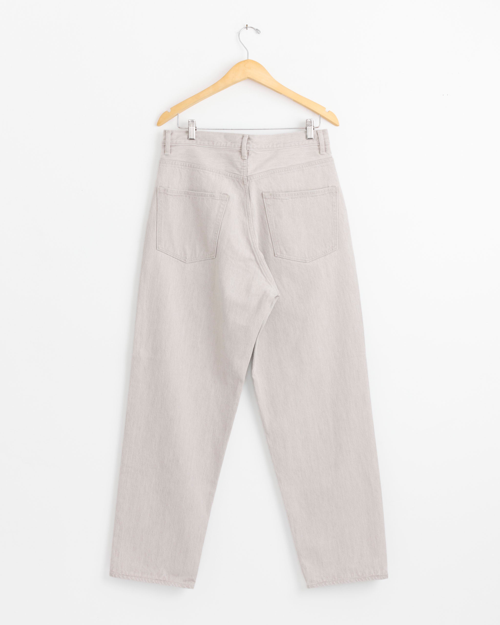 Auralee Faded Hard Twist Wide Pant in Light Grey, high-waisted and straight-leg, made in Japan, is displayed from the back on a wooden hanger against a white background, showing two rear pockets and belt loops.