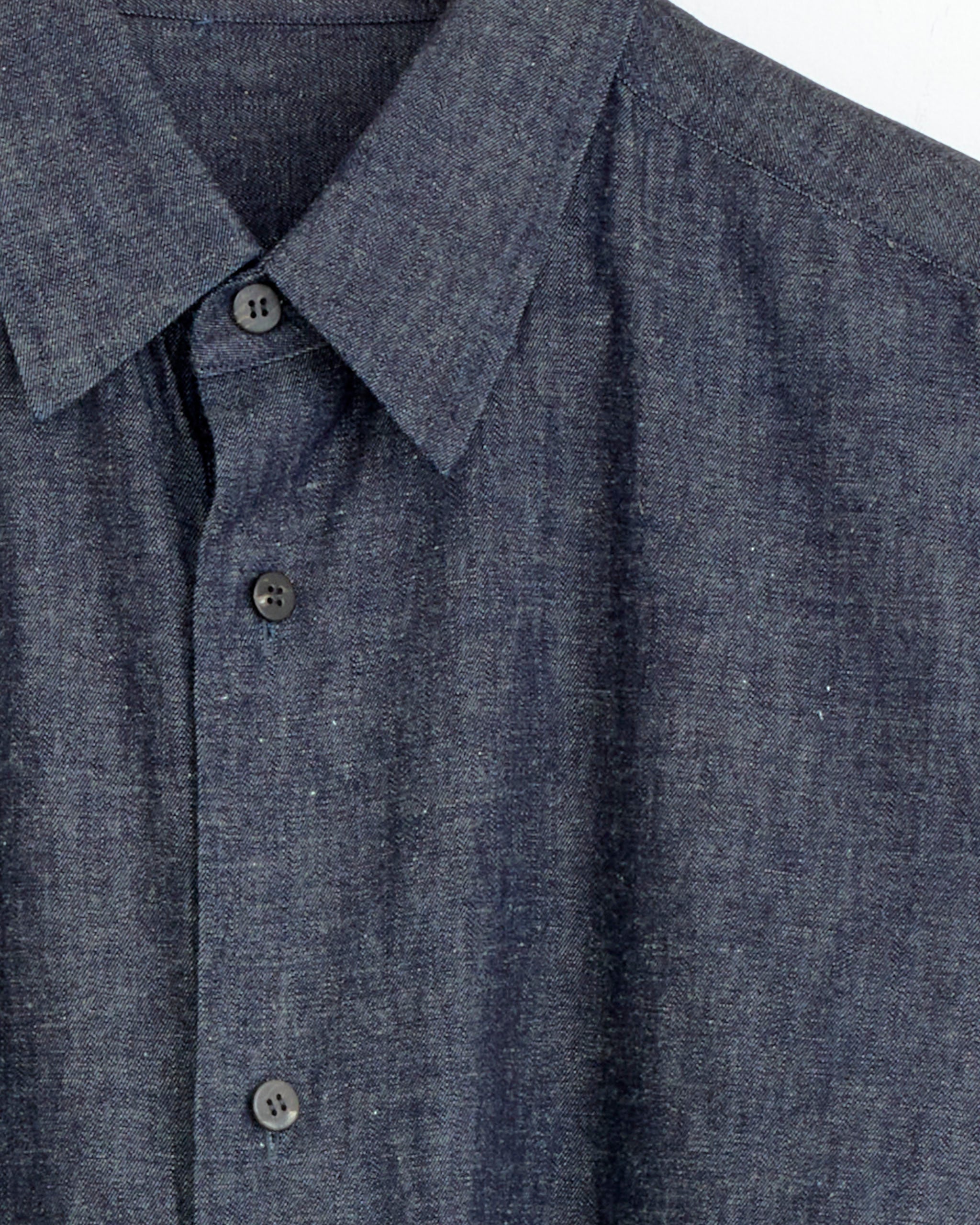 Close-up of the Cale Cotton Linen Ramie Denim Shirt in Navy, focusing on the collar, upper torso, visible buttons, and textured fabric.