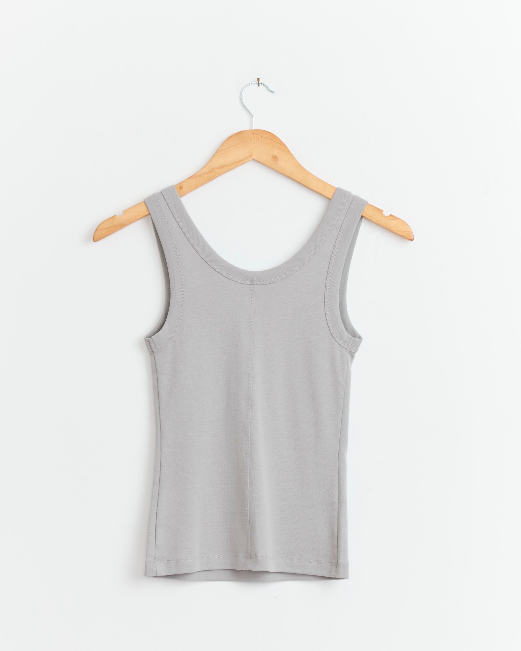The Hillie Tank in Mouse by FLORE FLORE, a light gray fitted scoop neck tank top, hangs on a wooden hanger against a plain white background.