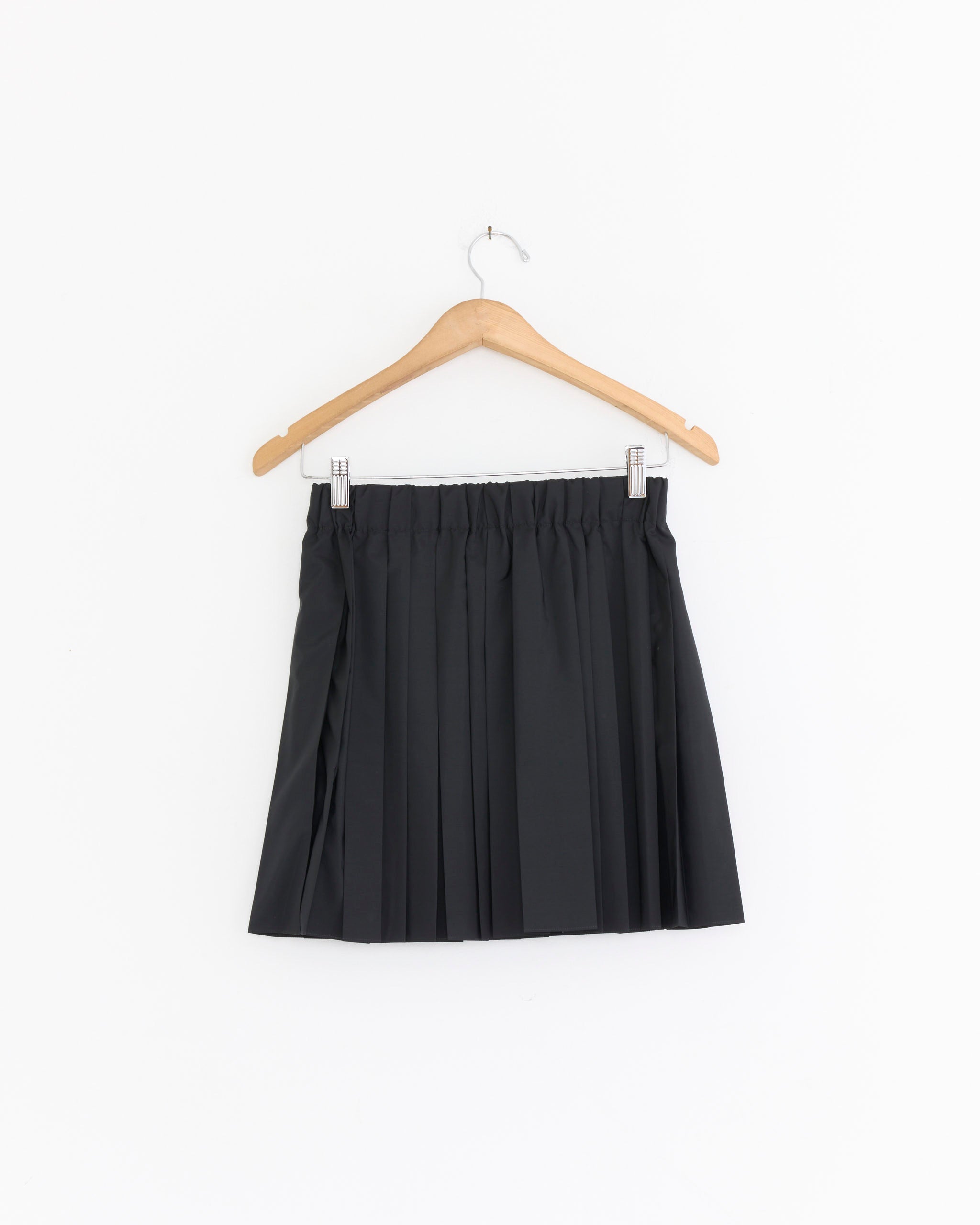 The Tibi Pull On Mini Skirt in Black is displayed on a wooden hanger against a plain white background.