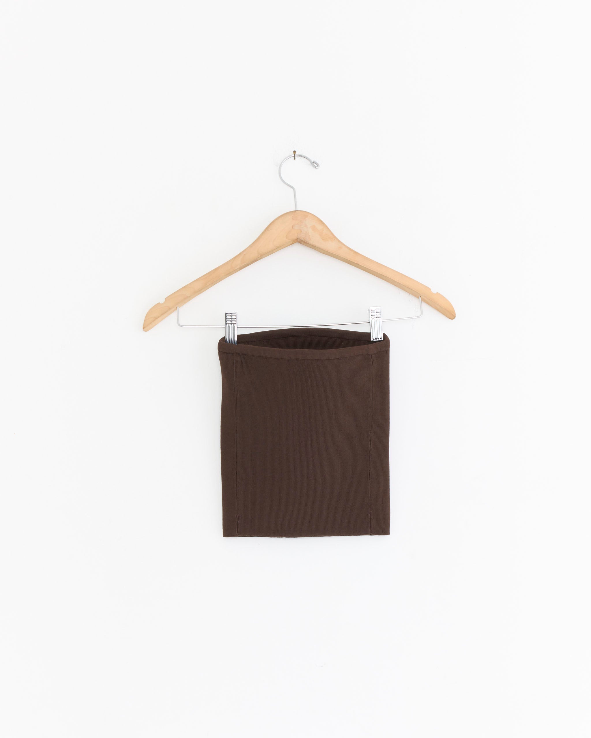 The Tibi Ribbed Tube Top in hickory brown hangs on a wooden hanger with metal clips against a plain white background—perfect for pairing with your favorite summer pieces.