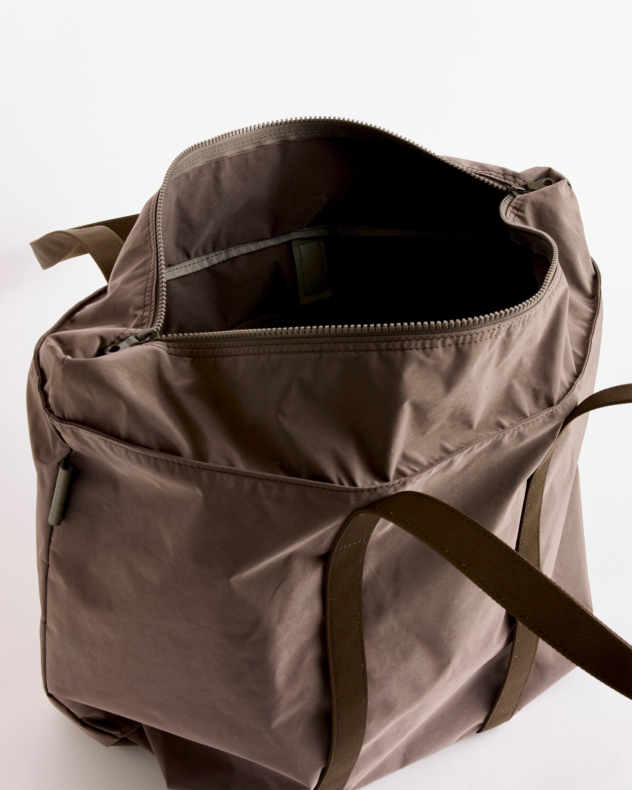 The Amiacalva Gabardine Tote in Grey, made in Japan, features a spacious interior, zipper closure, and two durable shoulder straps. Its lightweight fabric and elegant design stand out against a plain white background.