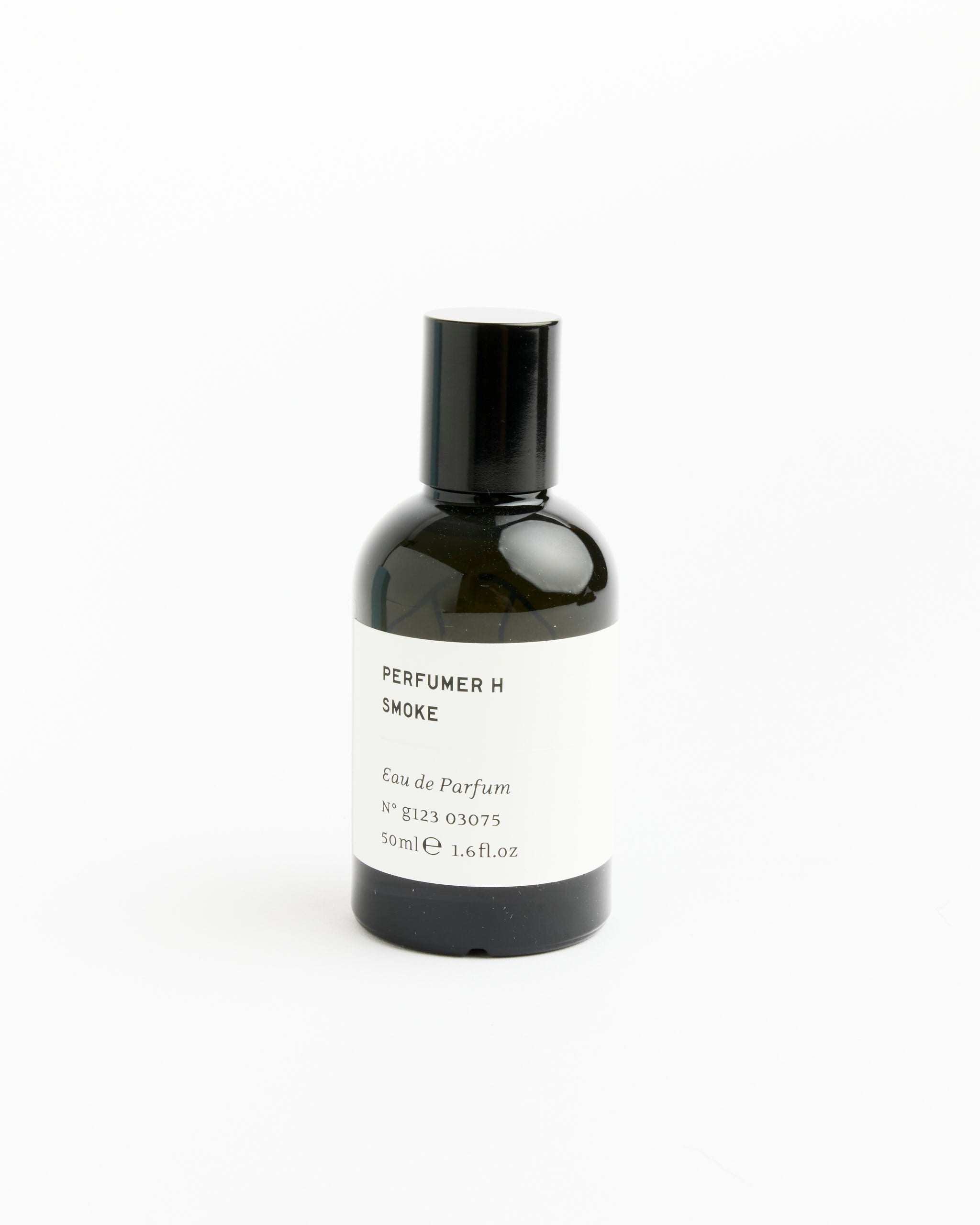 A dark glass bottle of Perfumer H Smoke Perfume, a woody amber fragrance, features a white label with the scent name and 50 ml (1.6 fl. oz) size, plus a black cap, shown against a plain white background.