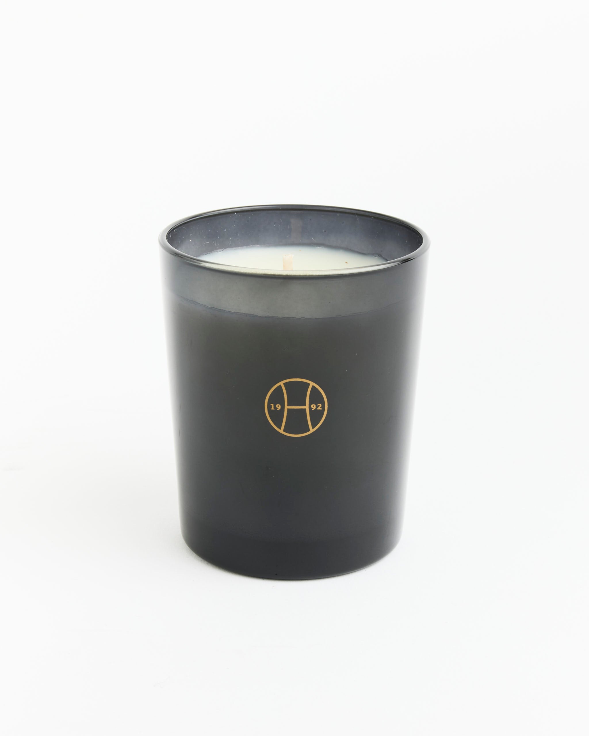 The Moss Candle by Perfumer H is hand poured in a matte black glass with a gold 19/92 logo, offering an earthy oak moss scent. Displayed on a white background.