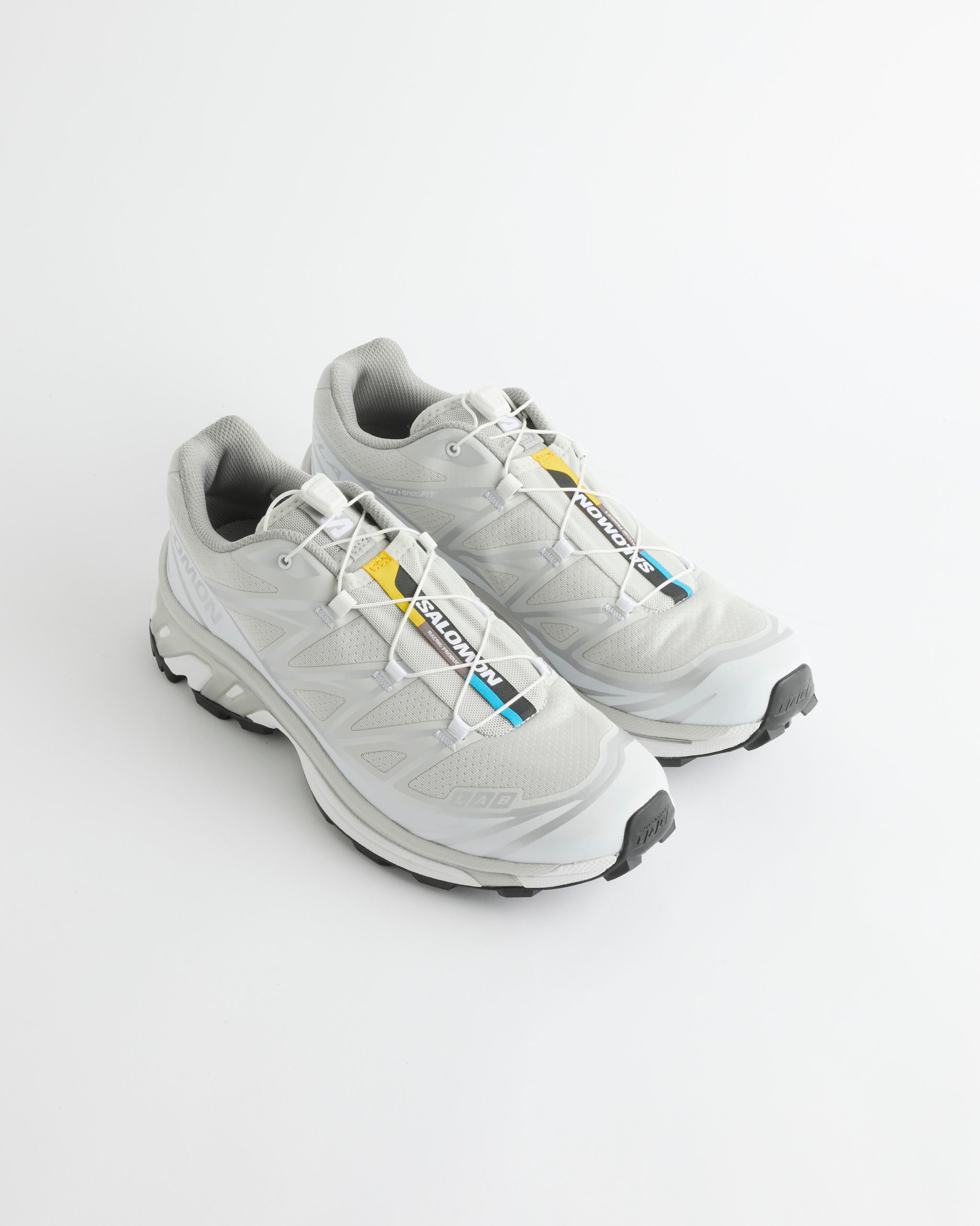 A pair of Salomon XT-6 sneakers in Lunar Rock/Ftw Silver/White with colorful tags on the laces, displayed on a plain white background.