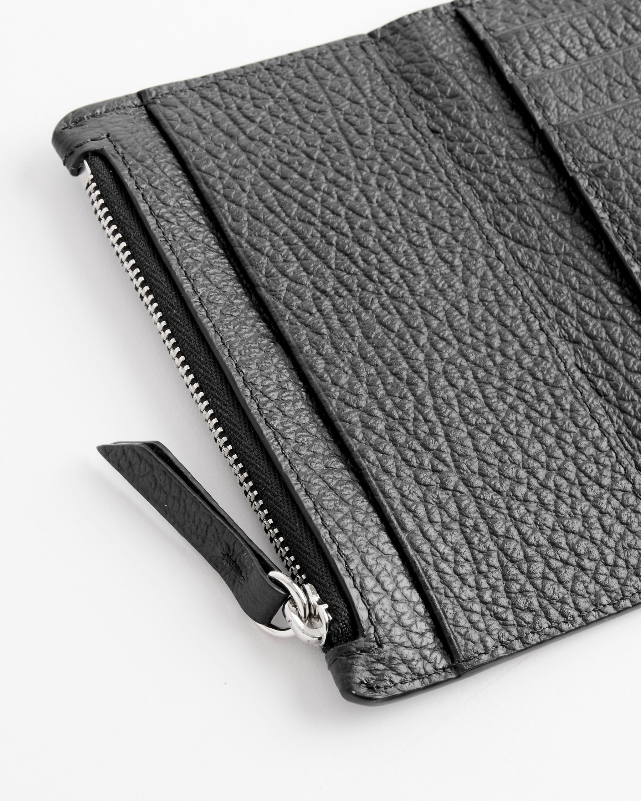 Close-up of the Maison Margiela Card Holder Clip 2 With Zip in Black, featuring textured leather, a silver zipper, and a leather pull tab, displayed on a white surface.