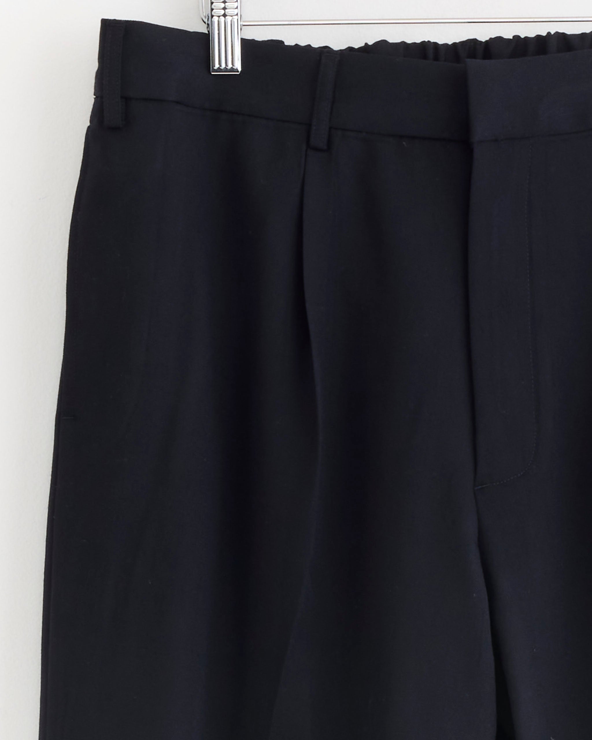 Close-up of SMOCK's West Coast Pant in Wool Gabardine Navy, highlighting the waistband, belt loops, and upper leg on a hanger against a plain light background.