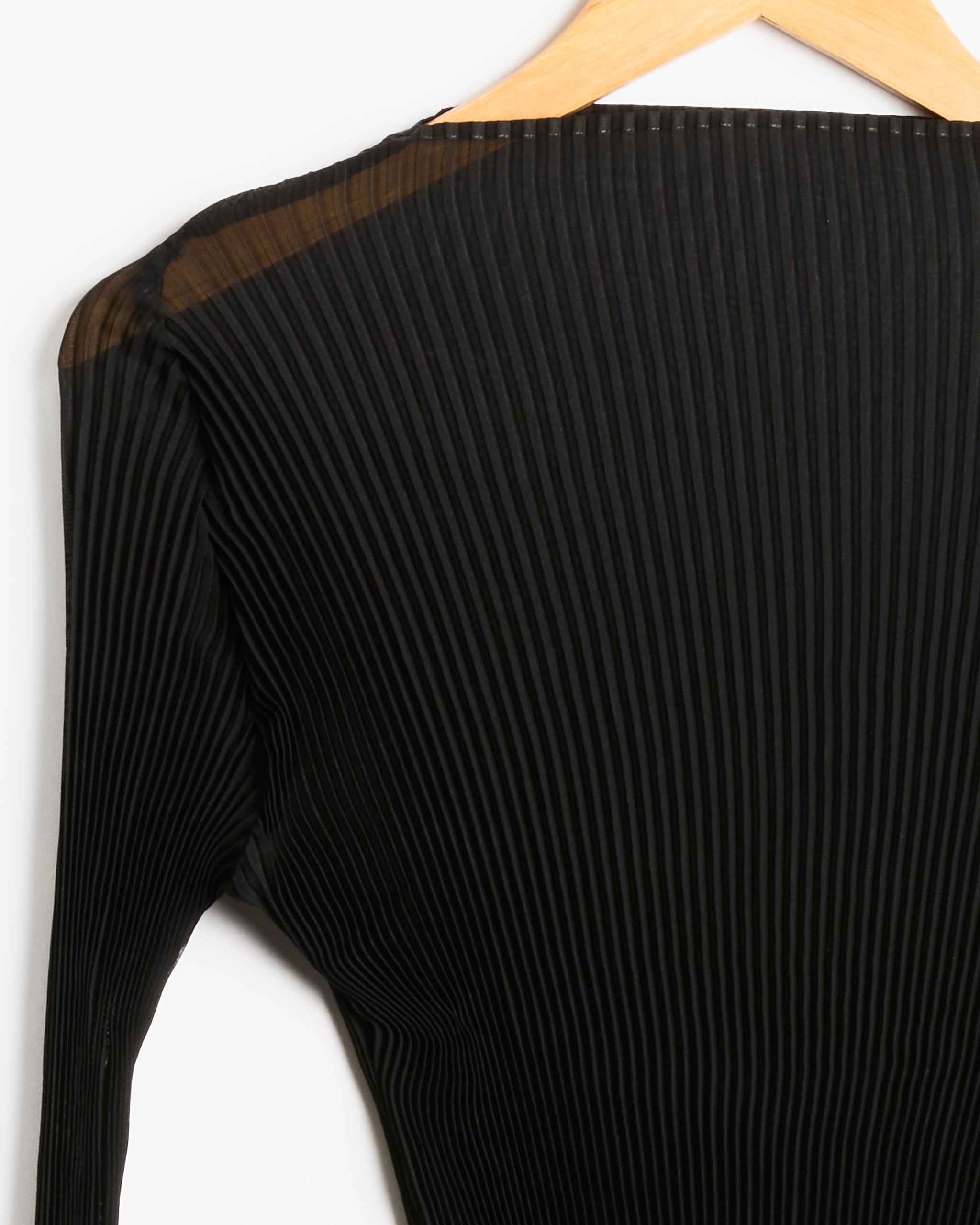 A close-up of the Julia Heuer Lee Top in Monochroms Black, featuring its ribbed fabric and long sleeves on a wooden hanger, with the shoulder and part of the sleeve visible against a plain white background.