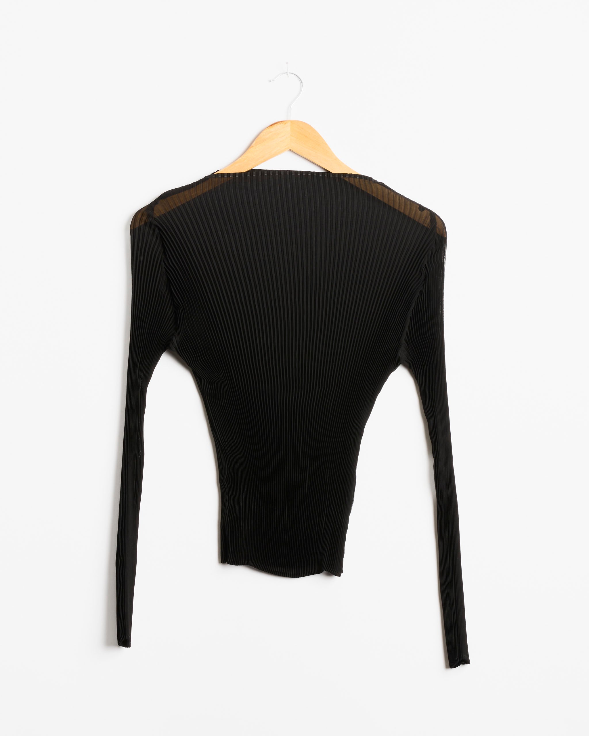 The Lee Top in Monochroms Black by Julia Heuer, featuring long sleeves and a ribbed texture, hangs on a wooden hanger against a white background.