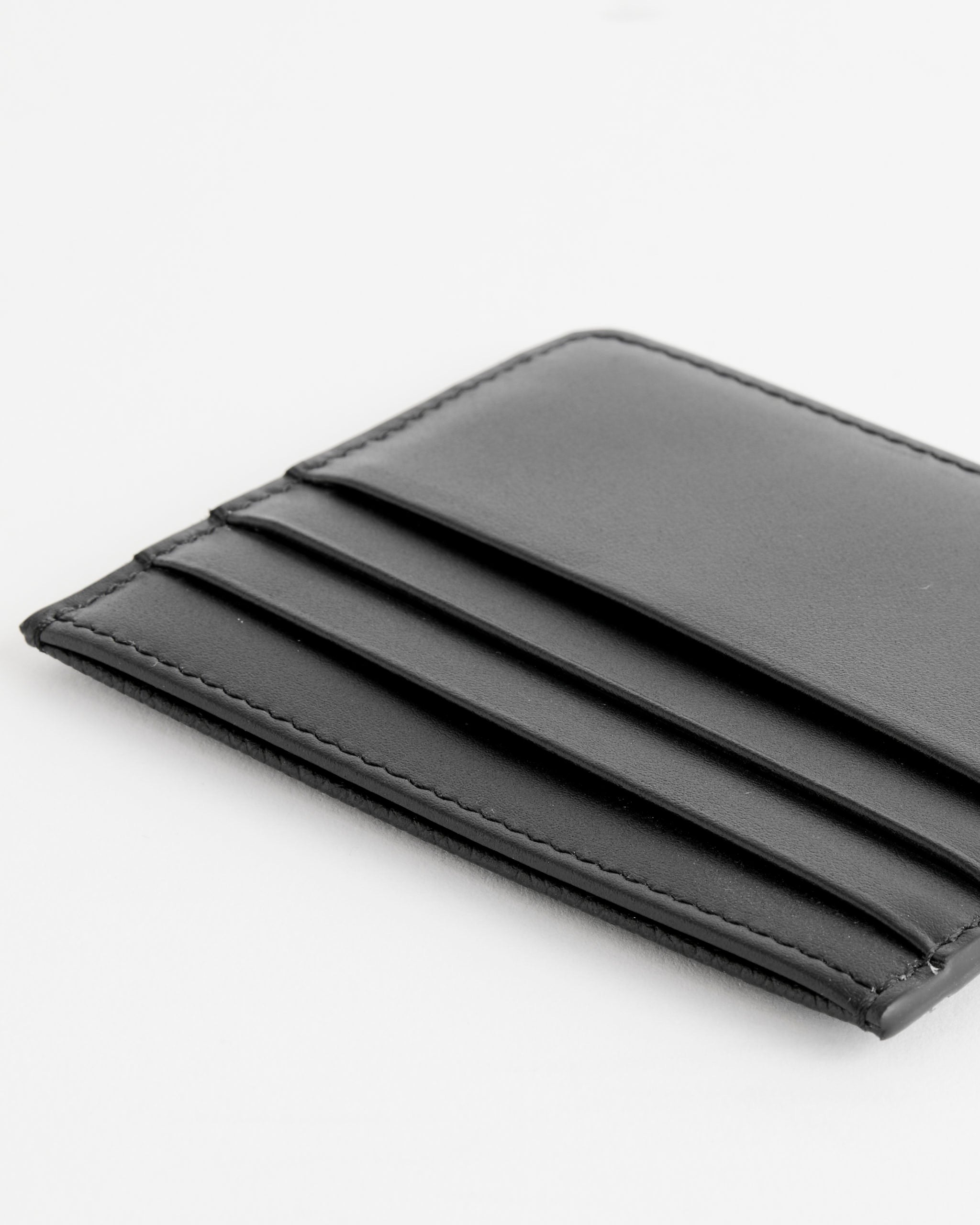 A close-up of the Maison Margiela Slim Card Holder in Black, crafted from grainy calf leather with multiple card slots in a slim design, set against a white background.